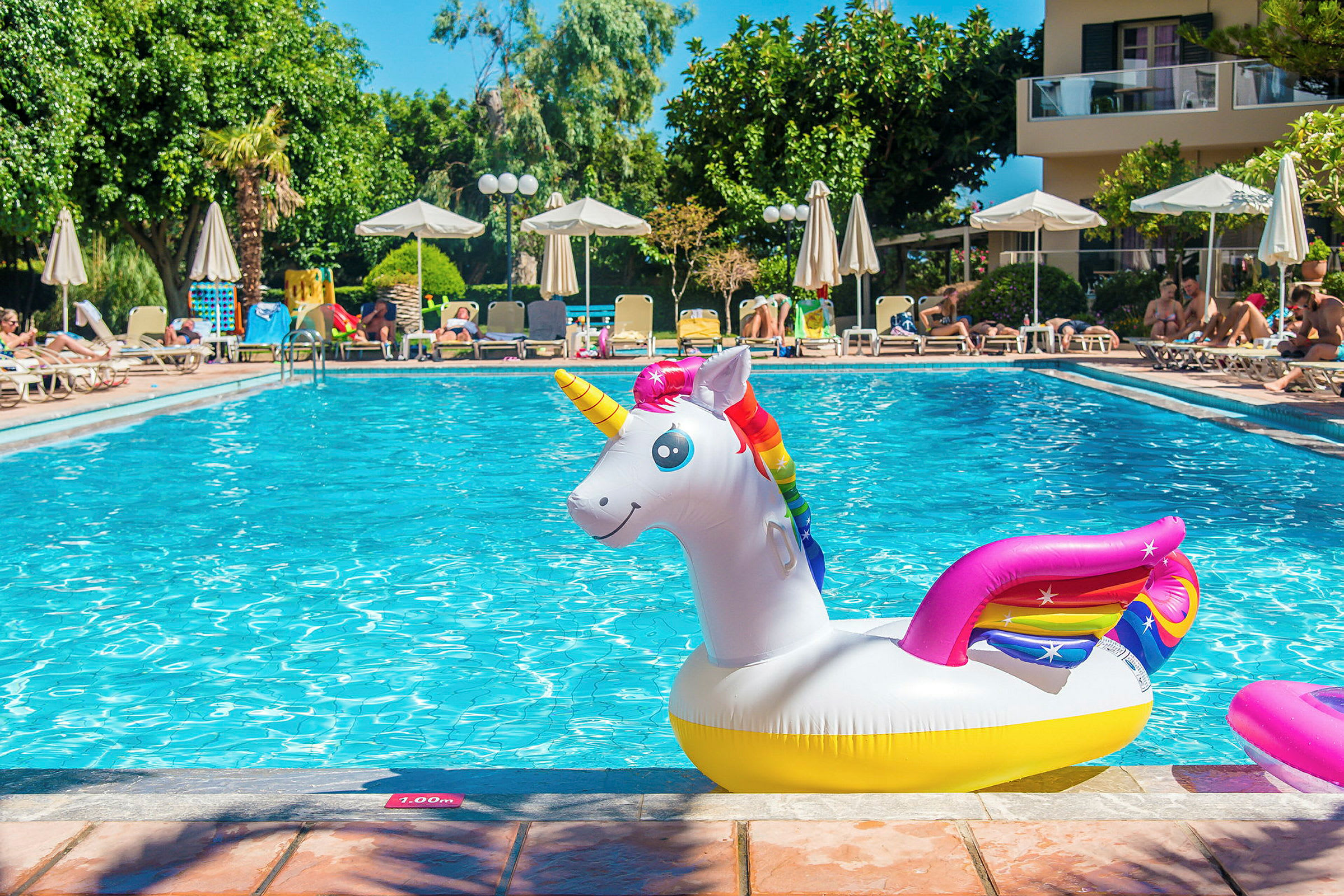 En pool med en uppblåsbar enhörning och solstolar i bakgrunden. (AI-genererad text)
