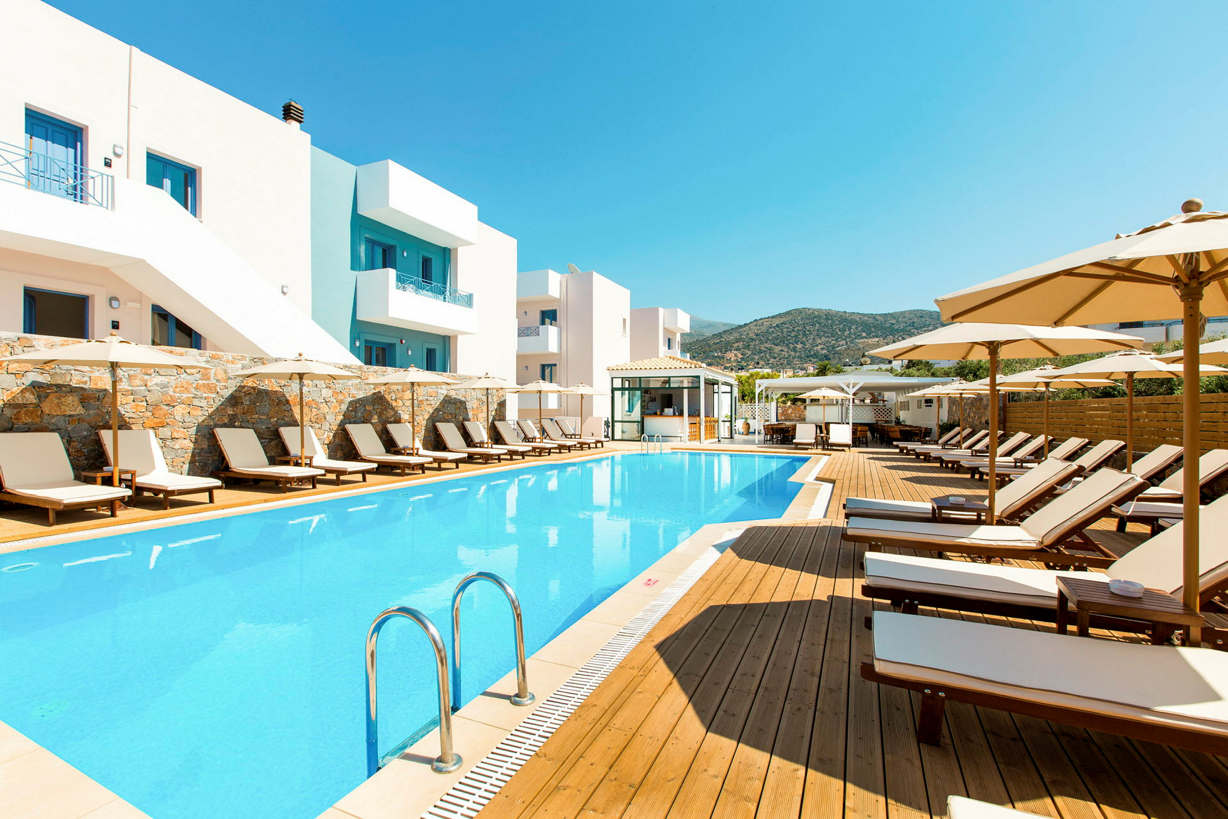 Utomhuspool och solstolar vid hotellbyggnad. (AI-genererad text)