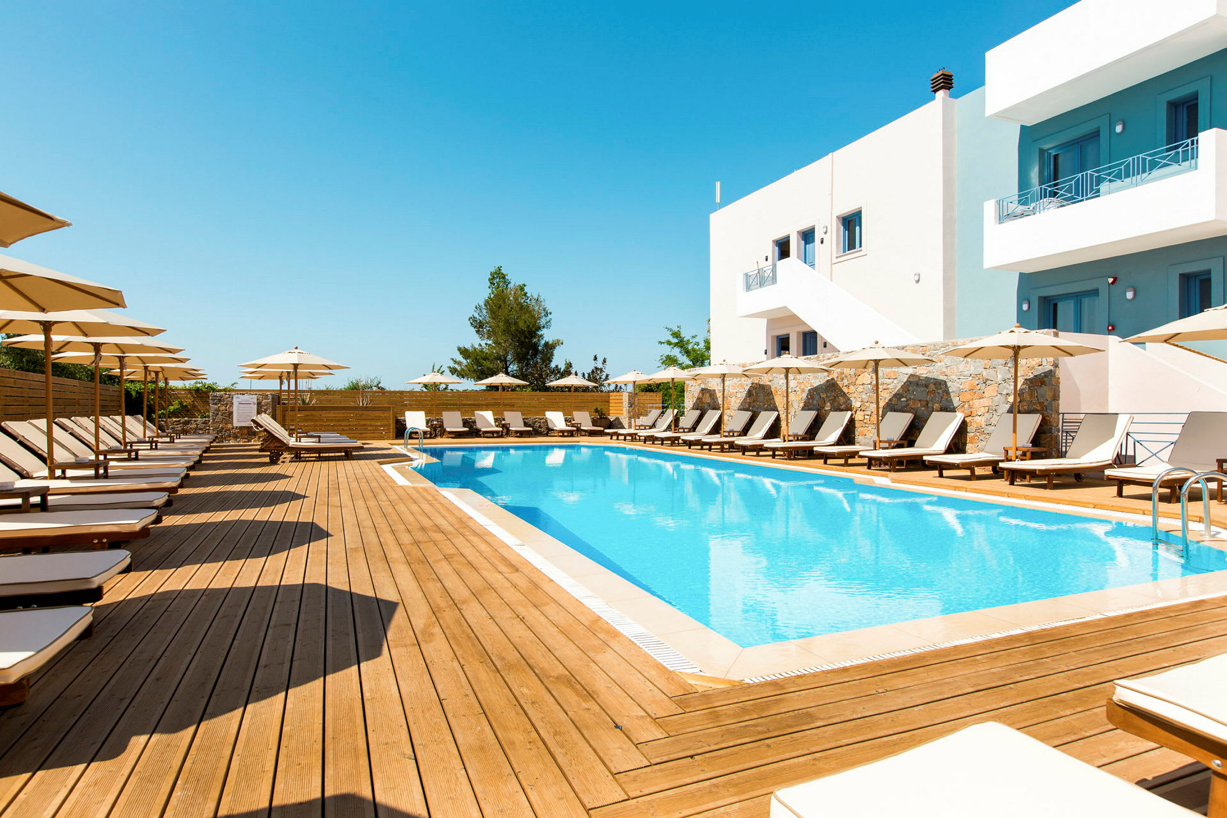 Utomhuspool med solstolar och parasoller kring ett hotellområde. (AI-genererad text)