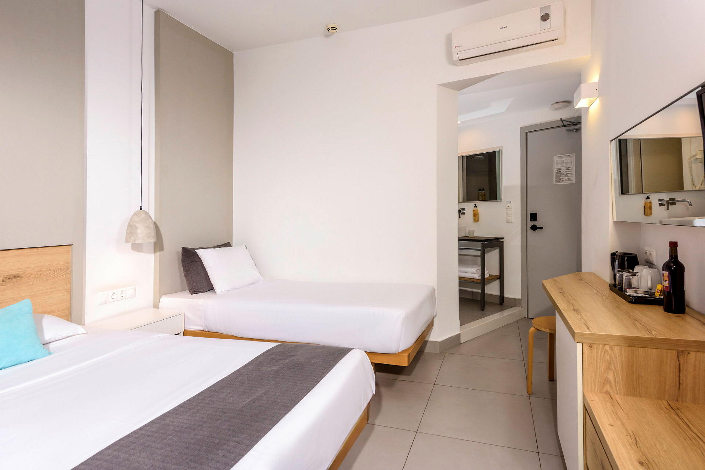 Ett hotellrum med två sängar, ett bord och en dörr till ett badrum. (AI-genererad text)