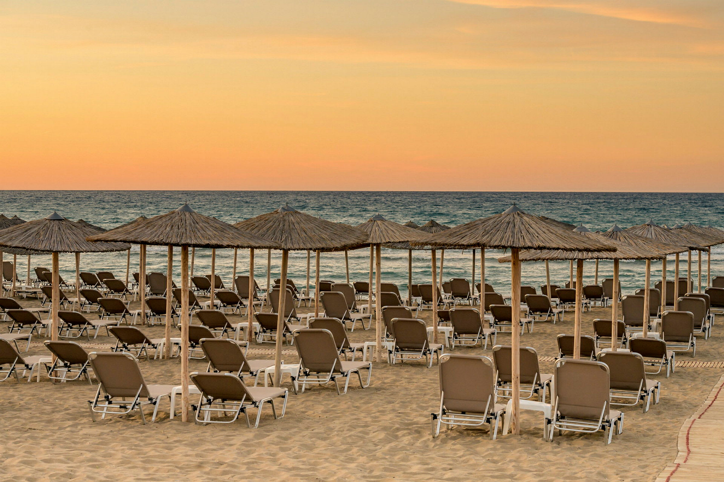 Strand med solstolar och parasoll vid solnedgång. (AI-genererad text)