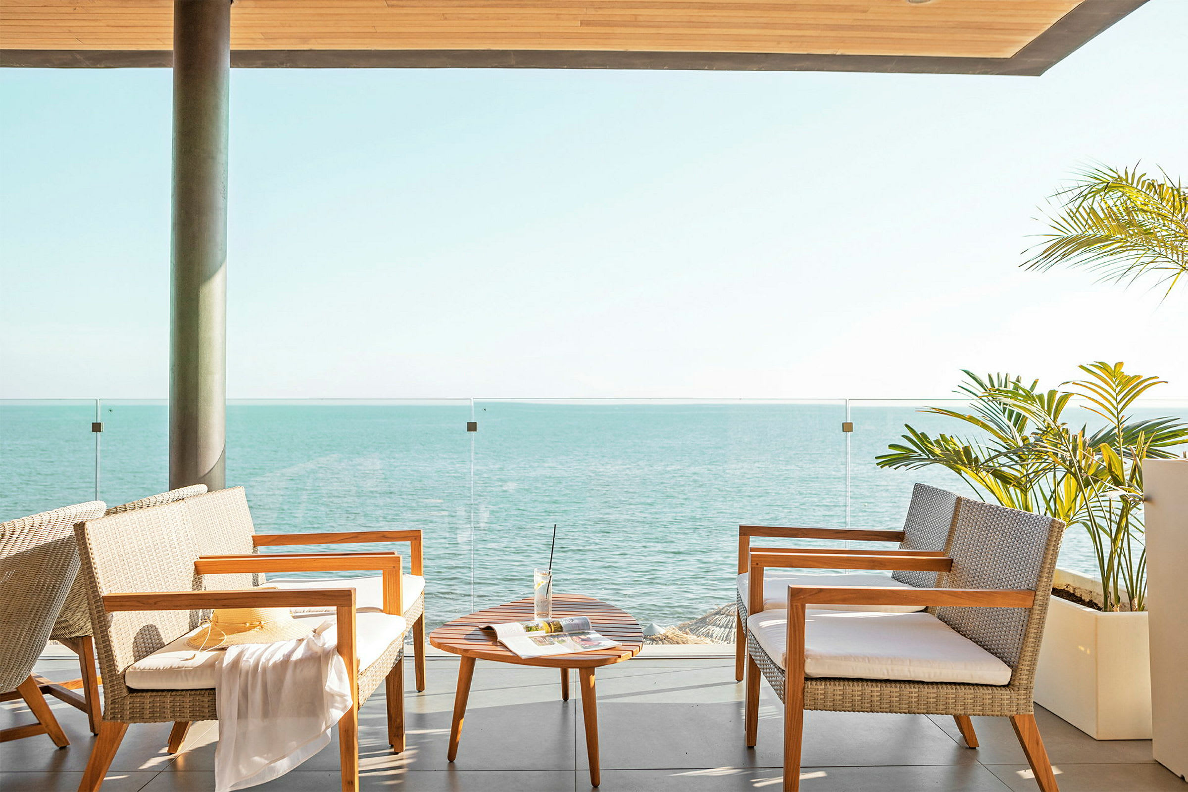 Terrass med sittmöbler, ett litet bord och utsikt över havet. (AI-genererad text)