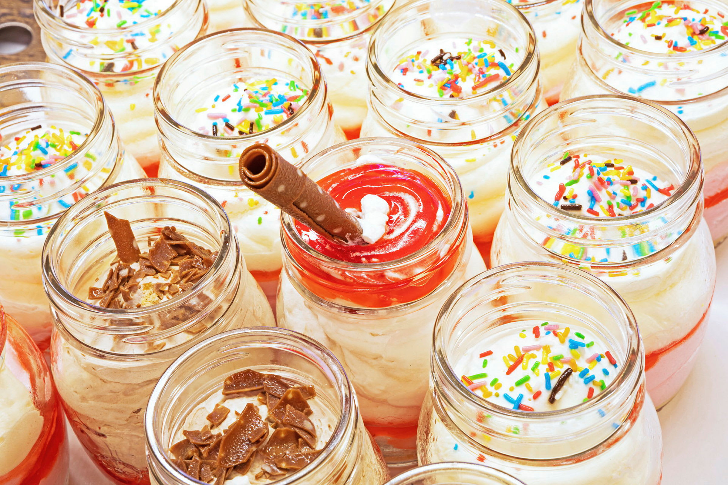 Glasburkar fyllda med dessert toppade med strössel och choklad. (AI-genererad text)