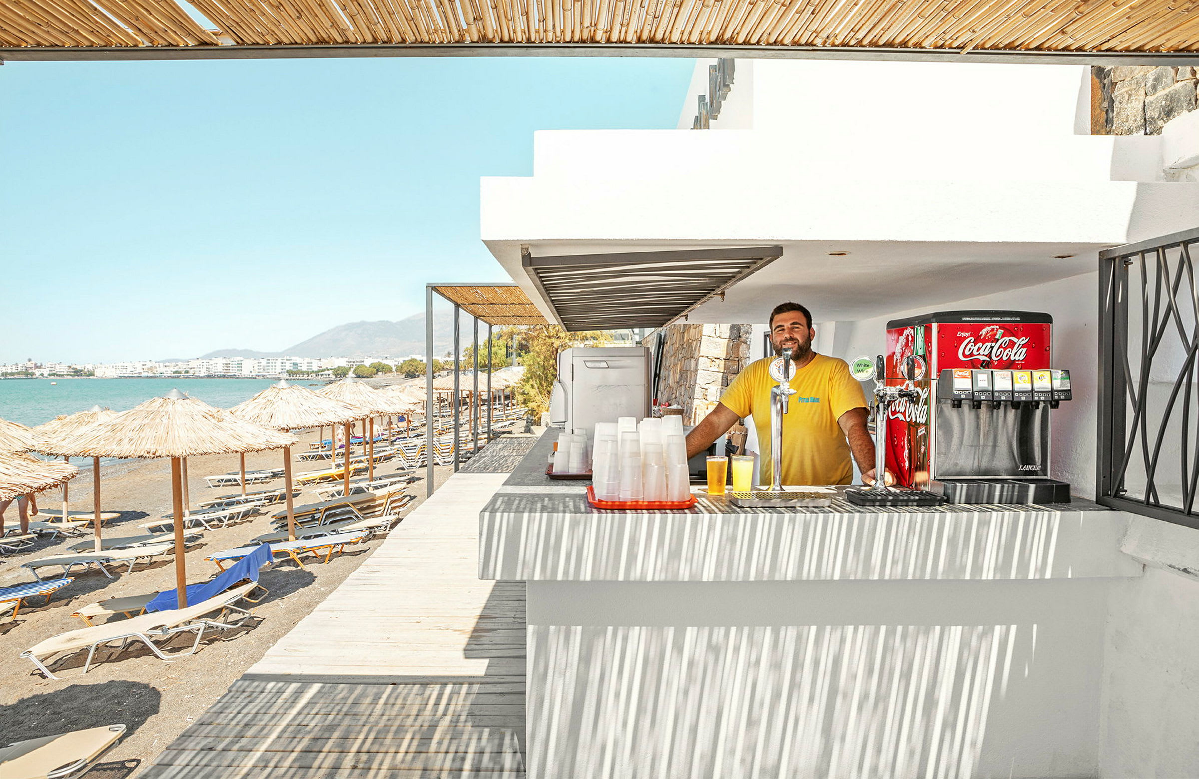 En strandbar vid havet med solstolar och parasoller på stranden. (AI-genererad text)