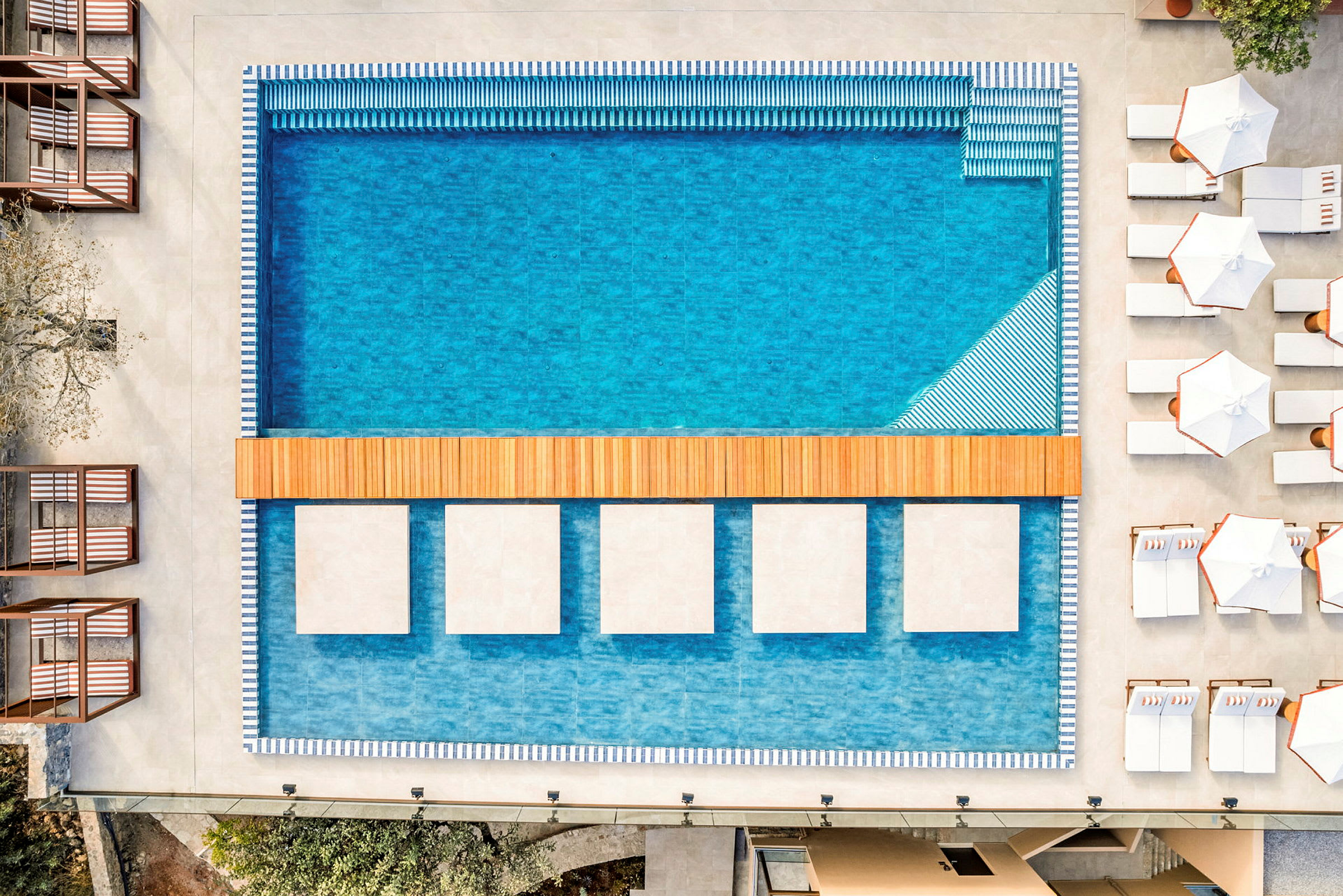 En modern swimmingpool omgiven av solsängar och parasoller. (AI-genererad text)