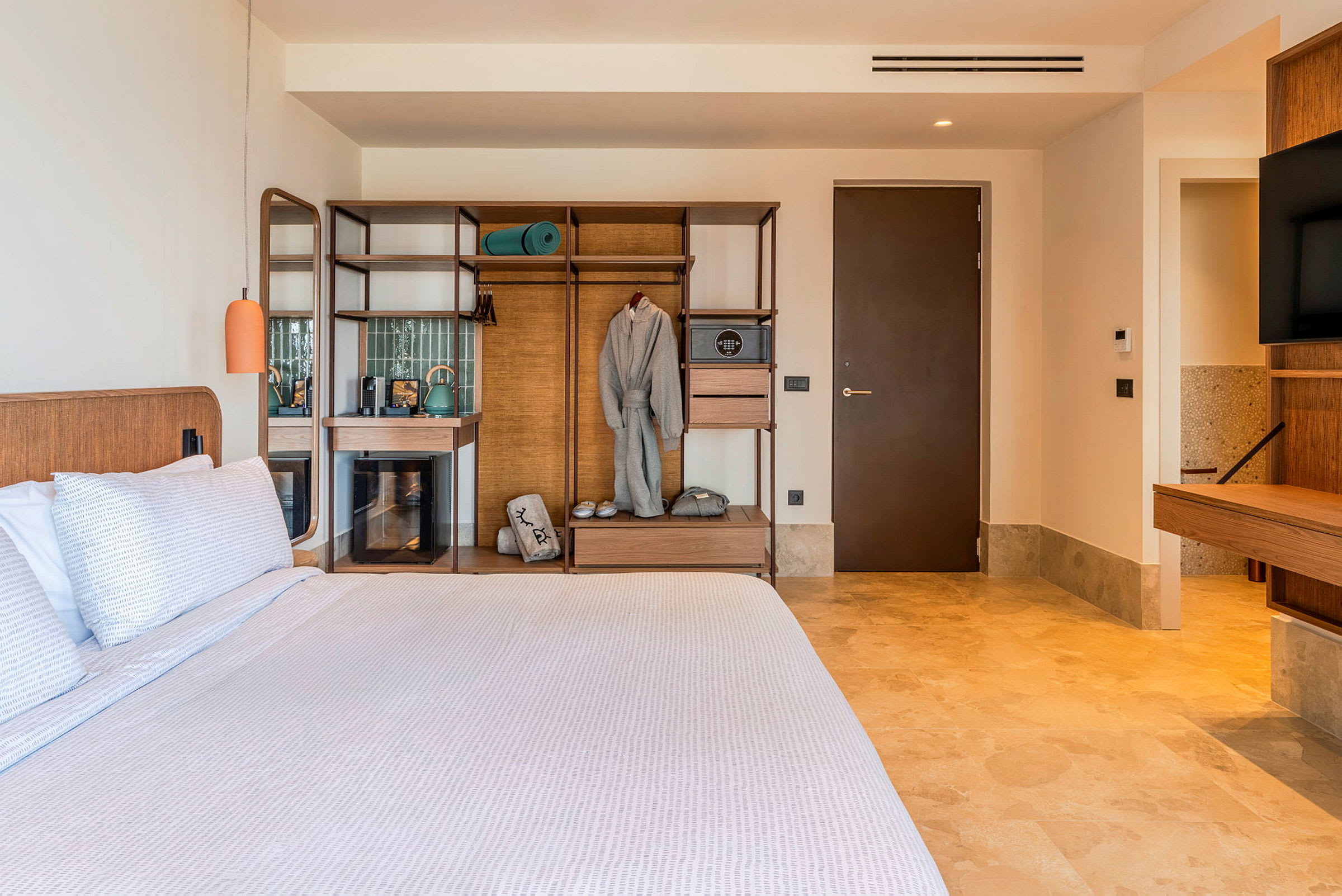 Ett hotellrum med en stor säng, trämöbler och en öppen garderob. (AI-genererad text)