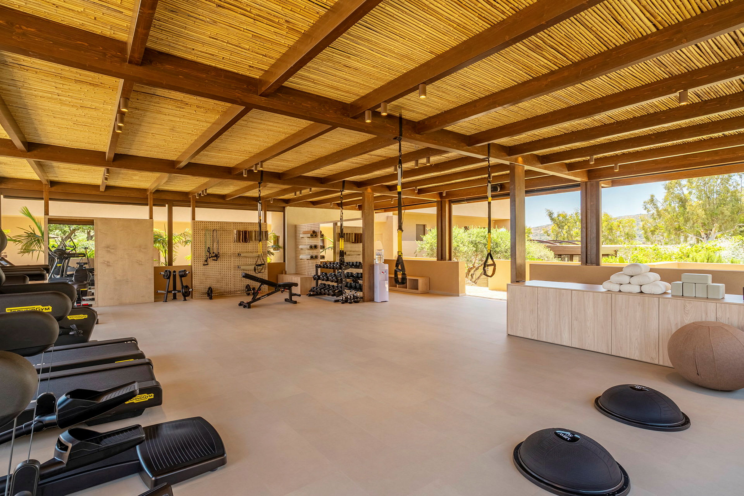 Ett gym med träningsmaskiner, redskap och öppet utrymme med takbjälkar av trä. (AI-genererad text)