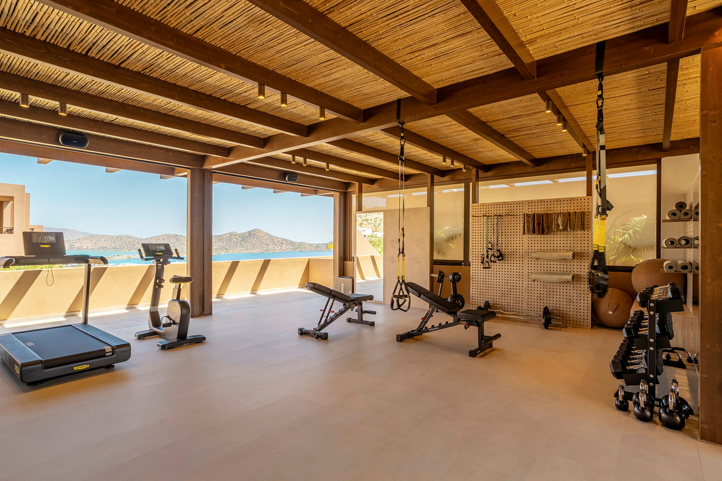 Ett modernt gym med träningsutrustning och utsikt över havet. (AI-genererad text)