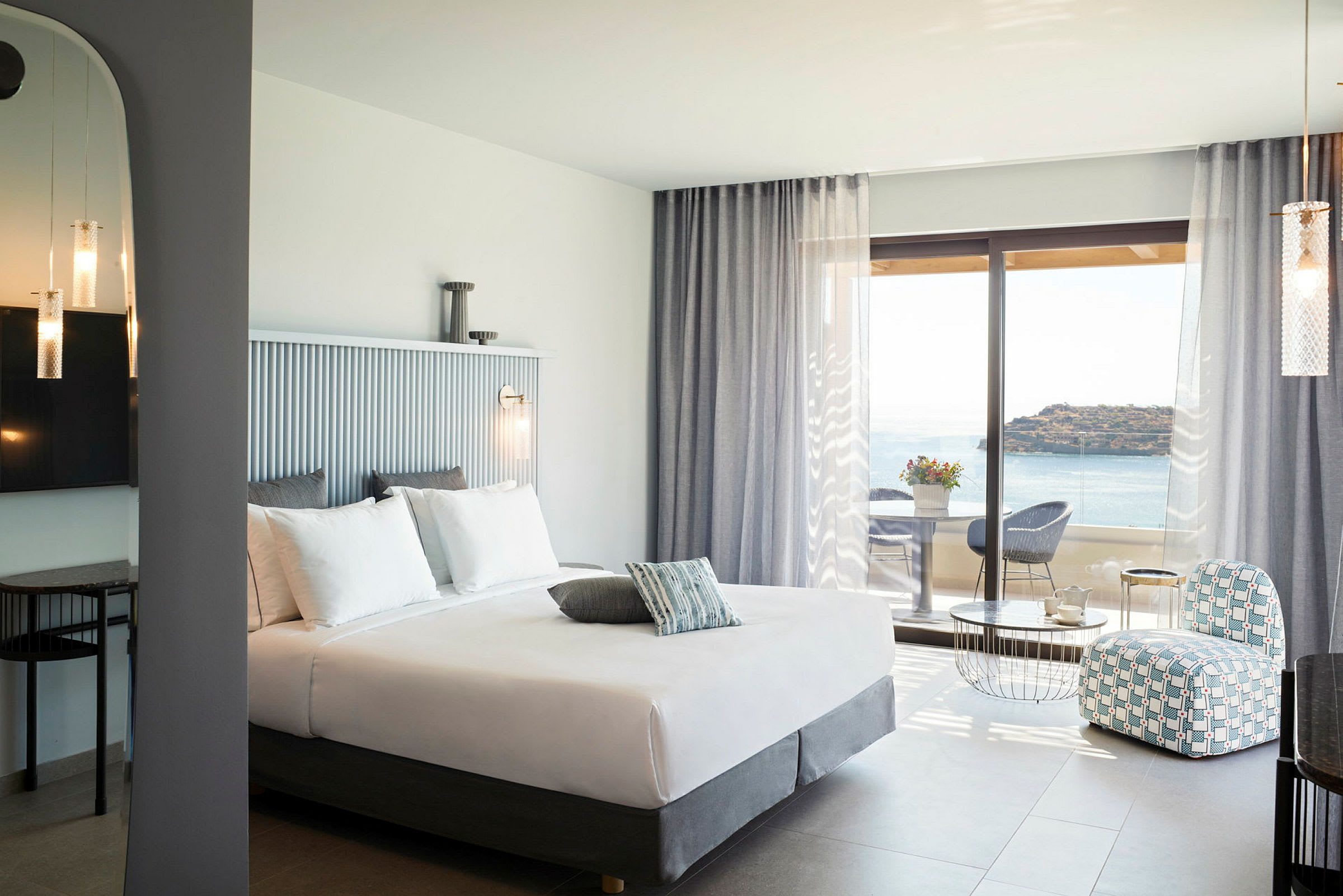 Hotellrum med dubbelsäng, sittgrupp och utsikt över havet. (AI-genererad text)