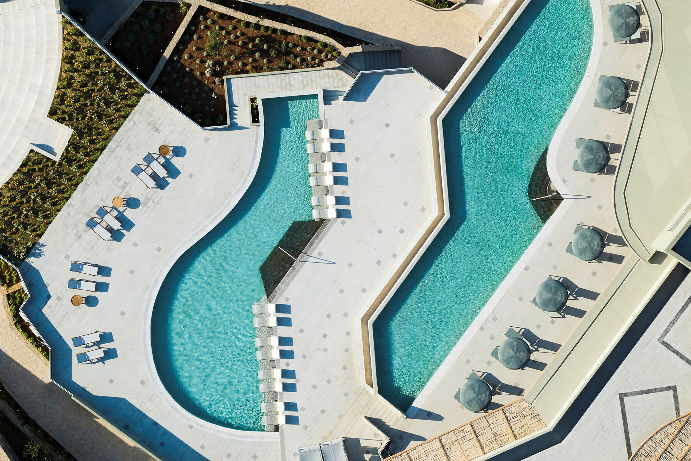 Flygbild över en modern pool med solstolar och parasoller. (AI-genererad text)