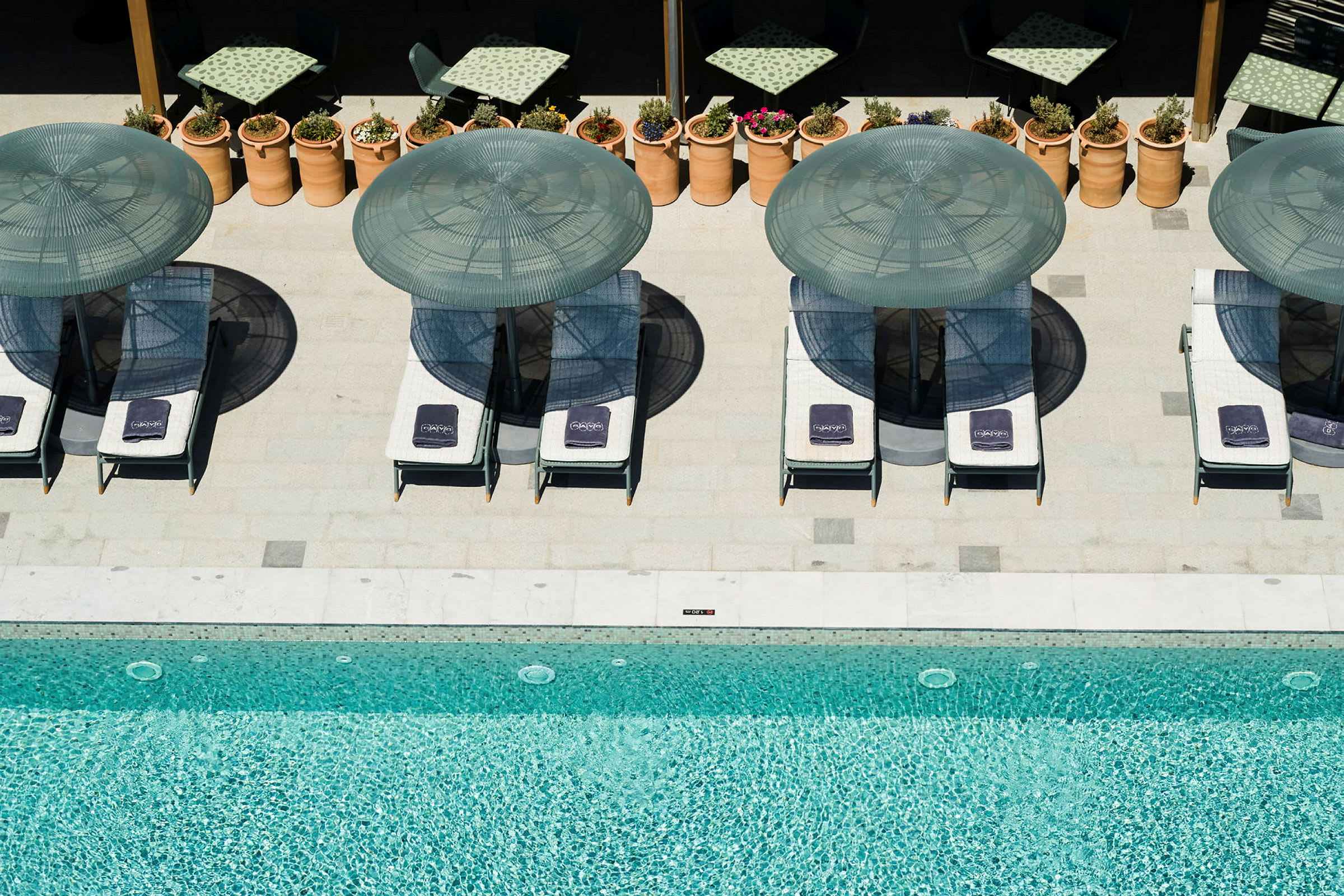 En pool med solparasoller och solstolar runt om. (AI-genererad text)