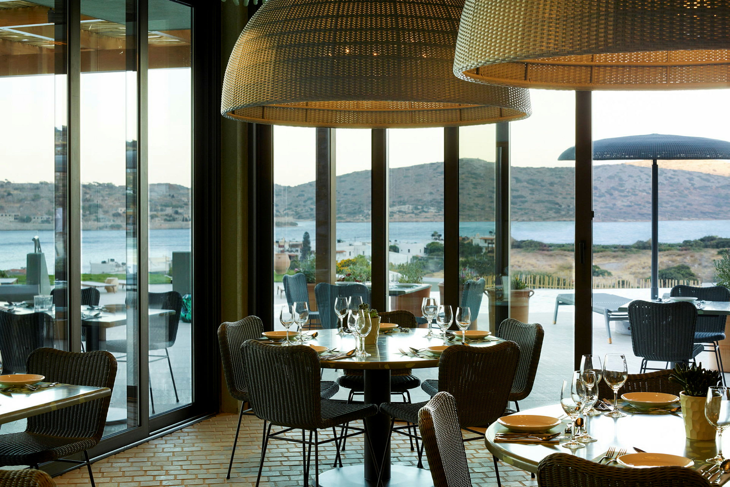 Restaurang med utsikt över havet och berg genom stora fönster. (AI-genererad text)