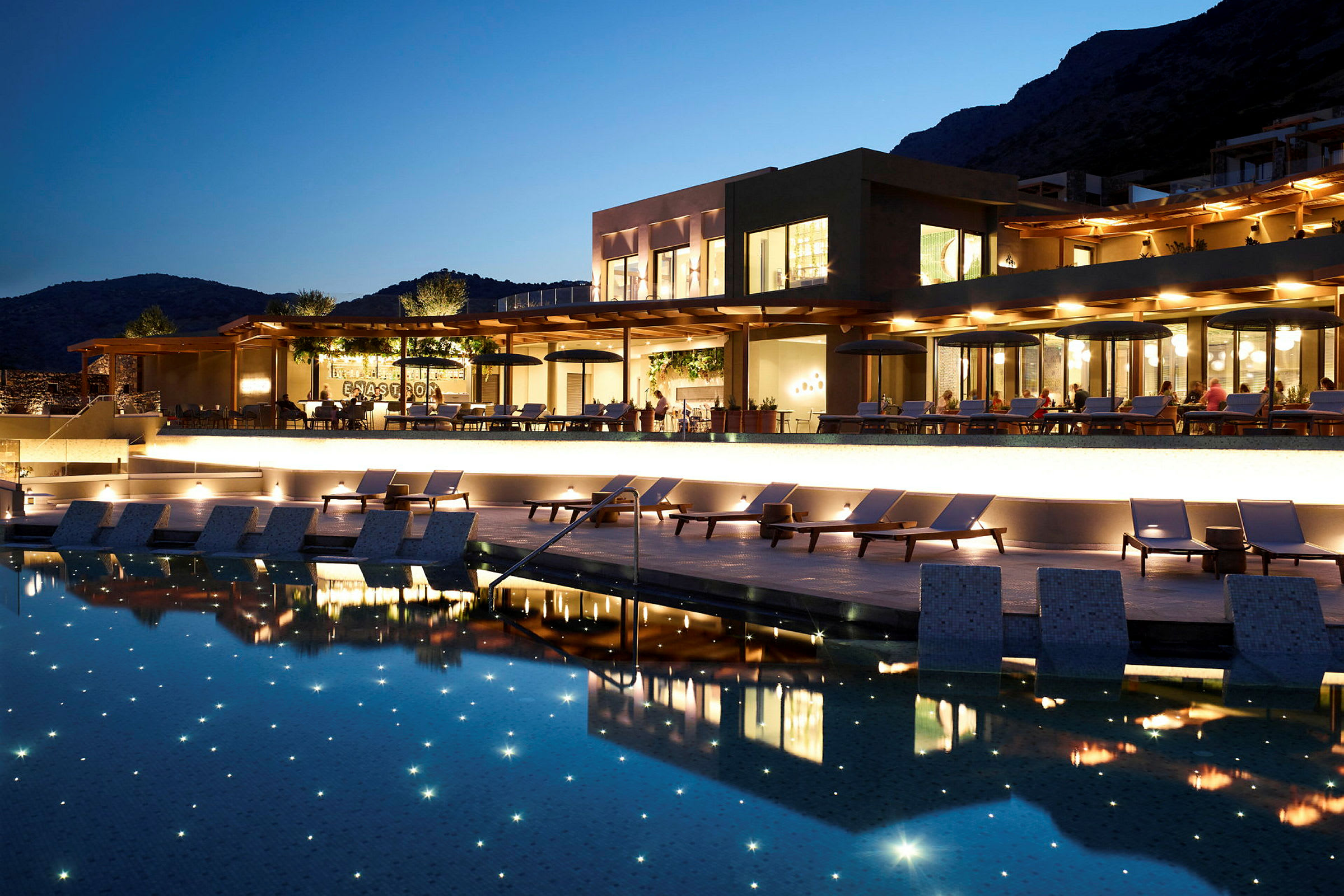 Upplyst hotellområde med solstolar och pool på kvällen. (AI-genererad text)