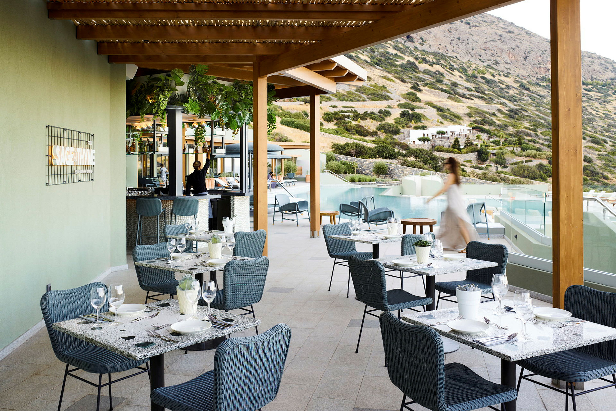 Utomhusrestaurang med sittplatser och utsikt över pool och berg. (AI-genererad text)