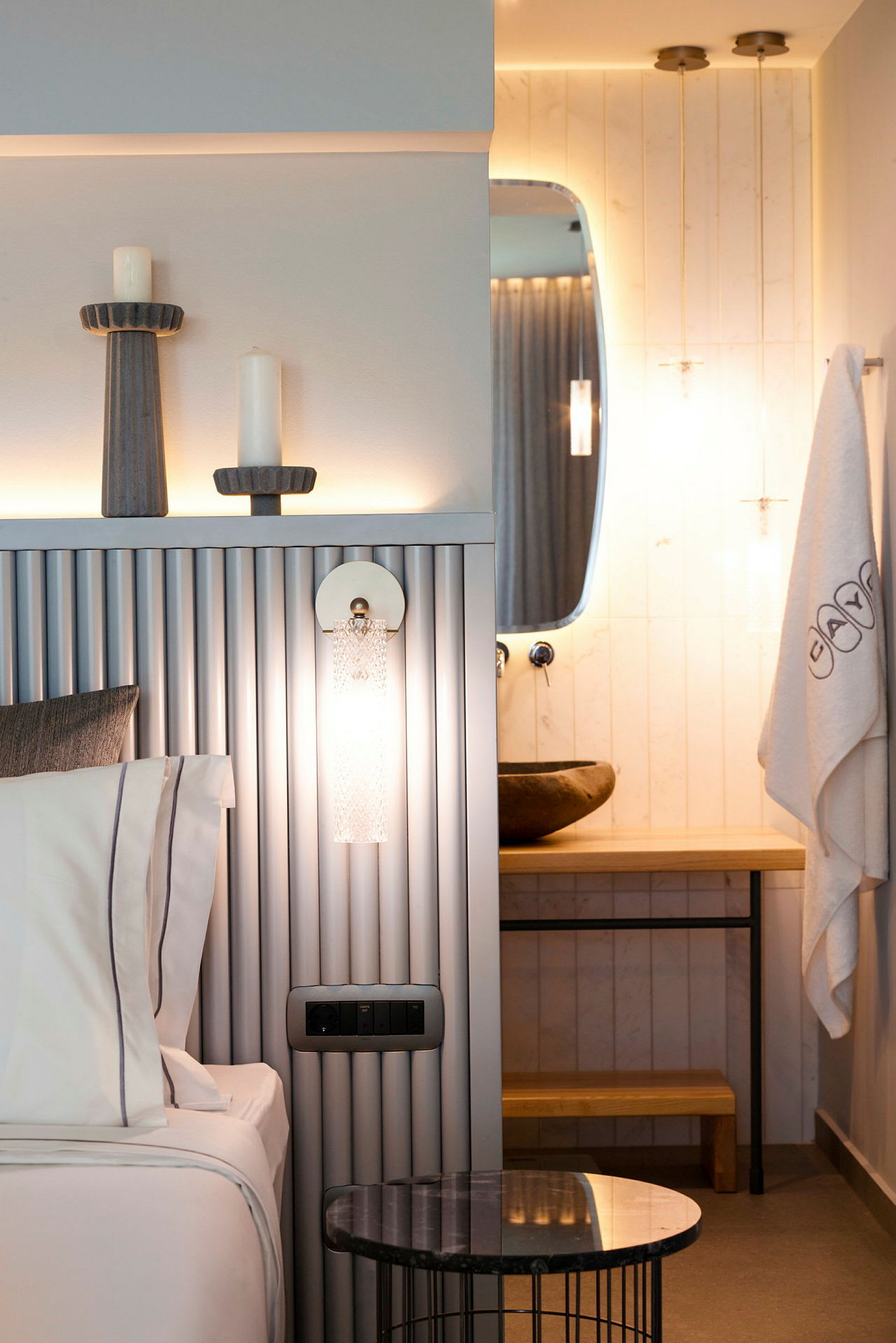 Ett modernt hotellrum med en säng, ett dekorativt bord och ett badrum med en spegel. (AI-genererad text)