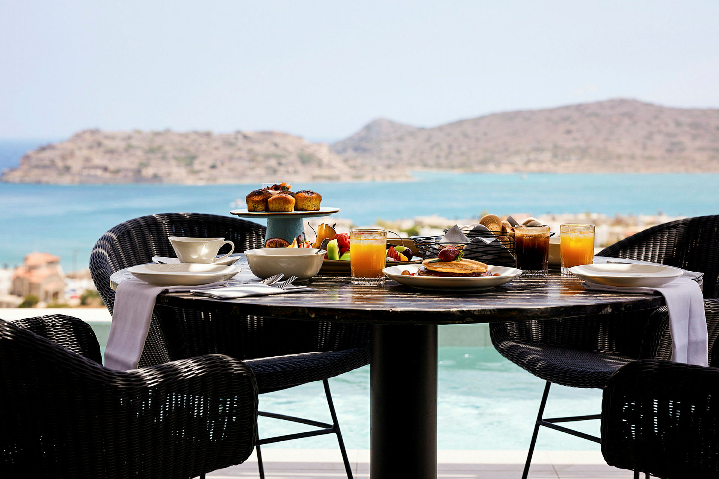 Ett frukostbord med mat och dryck med utsikt över havet. (AI-genererad text)