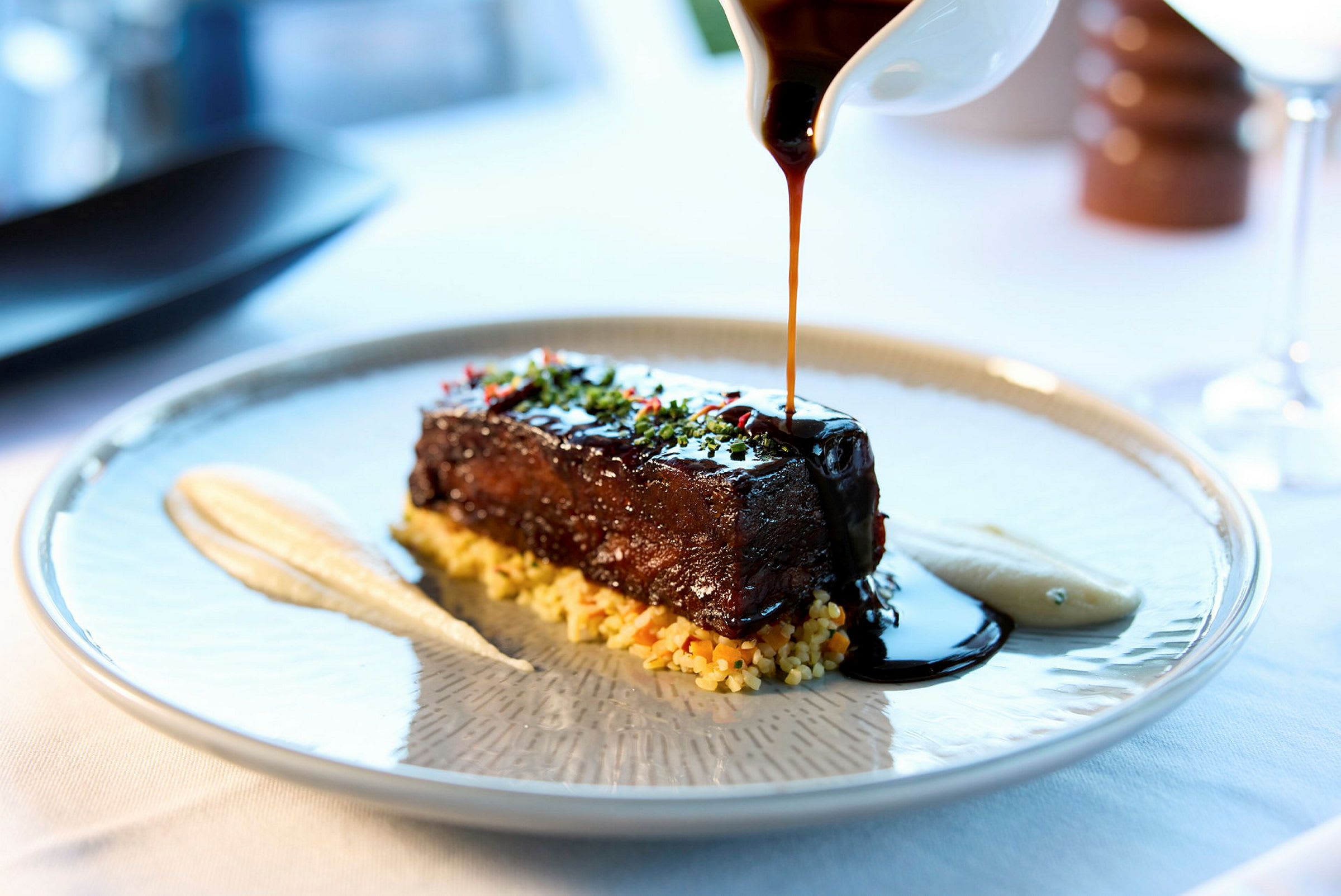 En maträtt med kött toppat med sås, serverad med pure och tillbehör på en tallrik. (AI-genererad text)