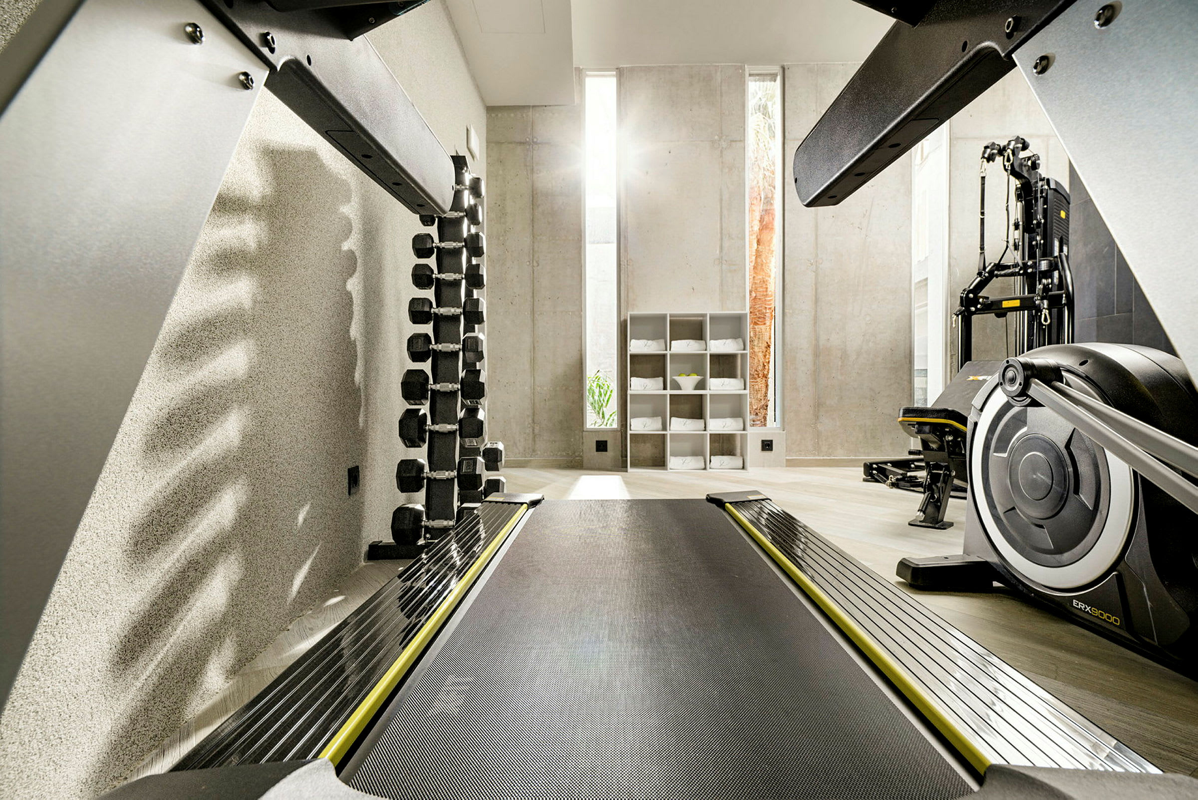 Ett gym med träningsmaskiner, hantlar och hyllor med handdukar. (AI-genererad text)