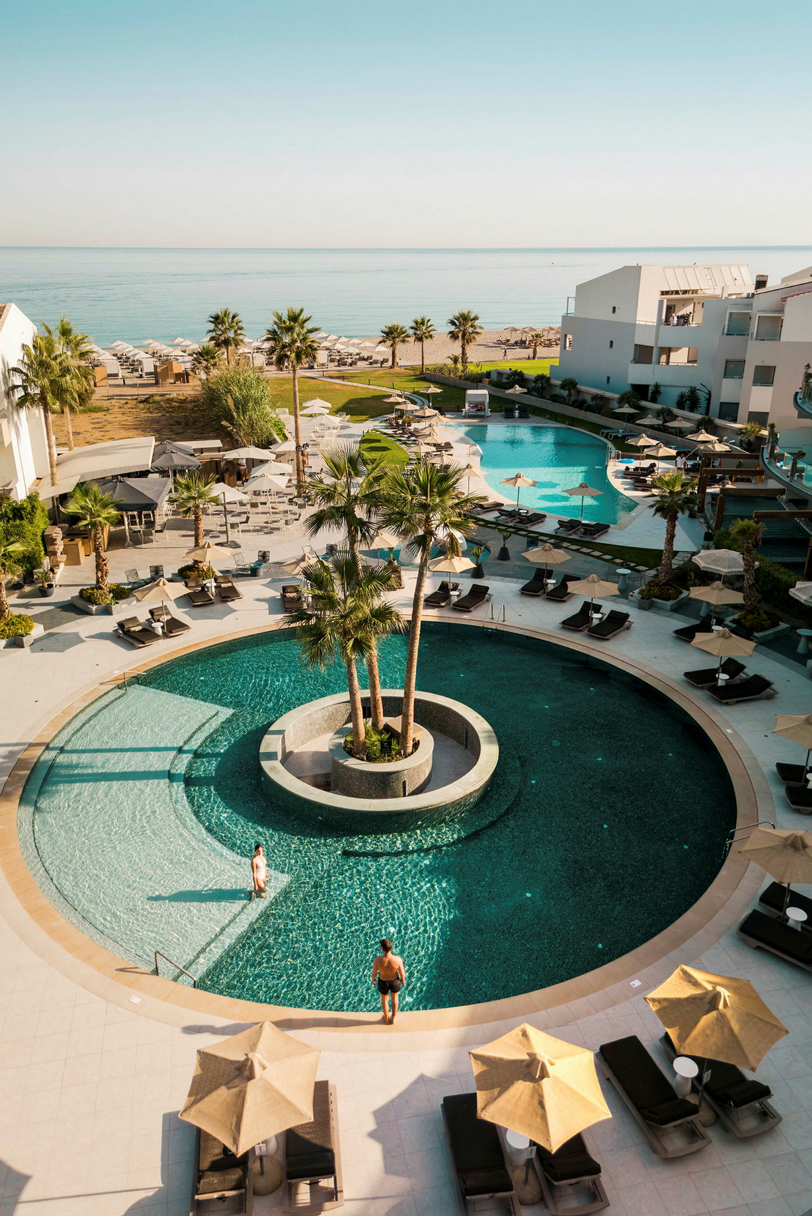 Bild av en resort med poolområde, solstolar och parasoller vid havet. (AI-genererad text)