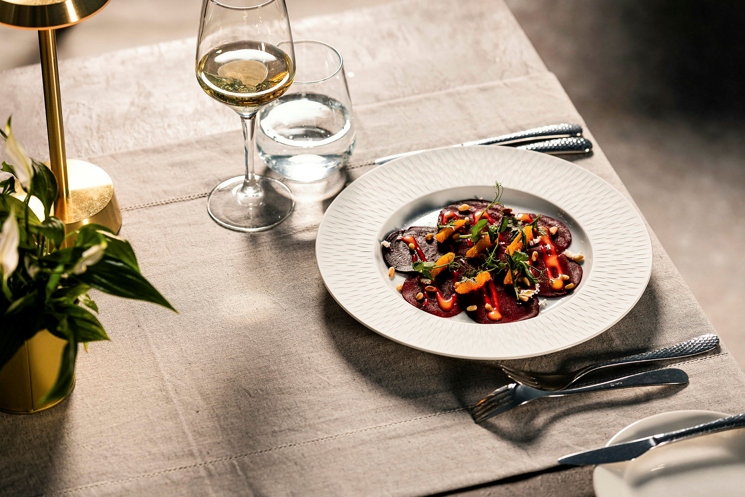 En tallrik med en gourmetförrätt av rödbetor och tillbehör på ett dukat bord. (AI-genererad text)