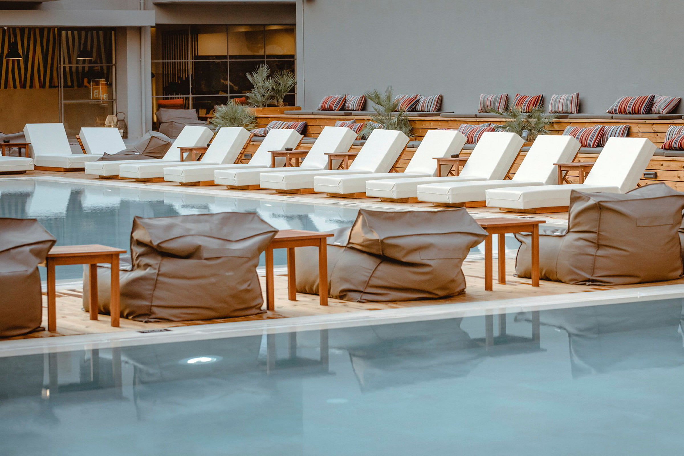 Liggande solstolar och saccosäckar vid en pool. (AI-genererad text)