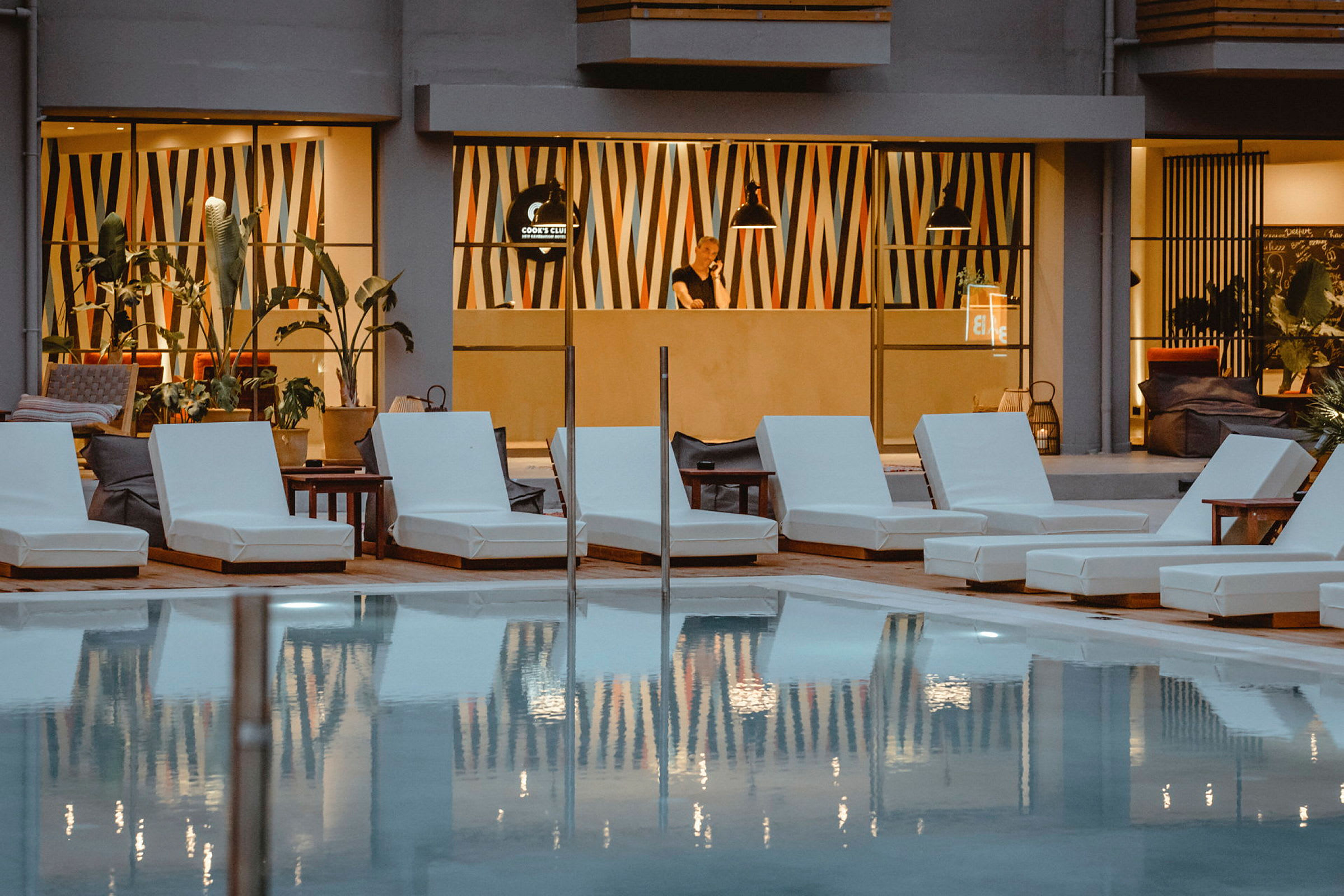 Utomhusområde med en pool, solstolar och moderna dekorationer i bakgrunden. (AI-genererad text)