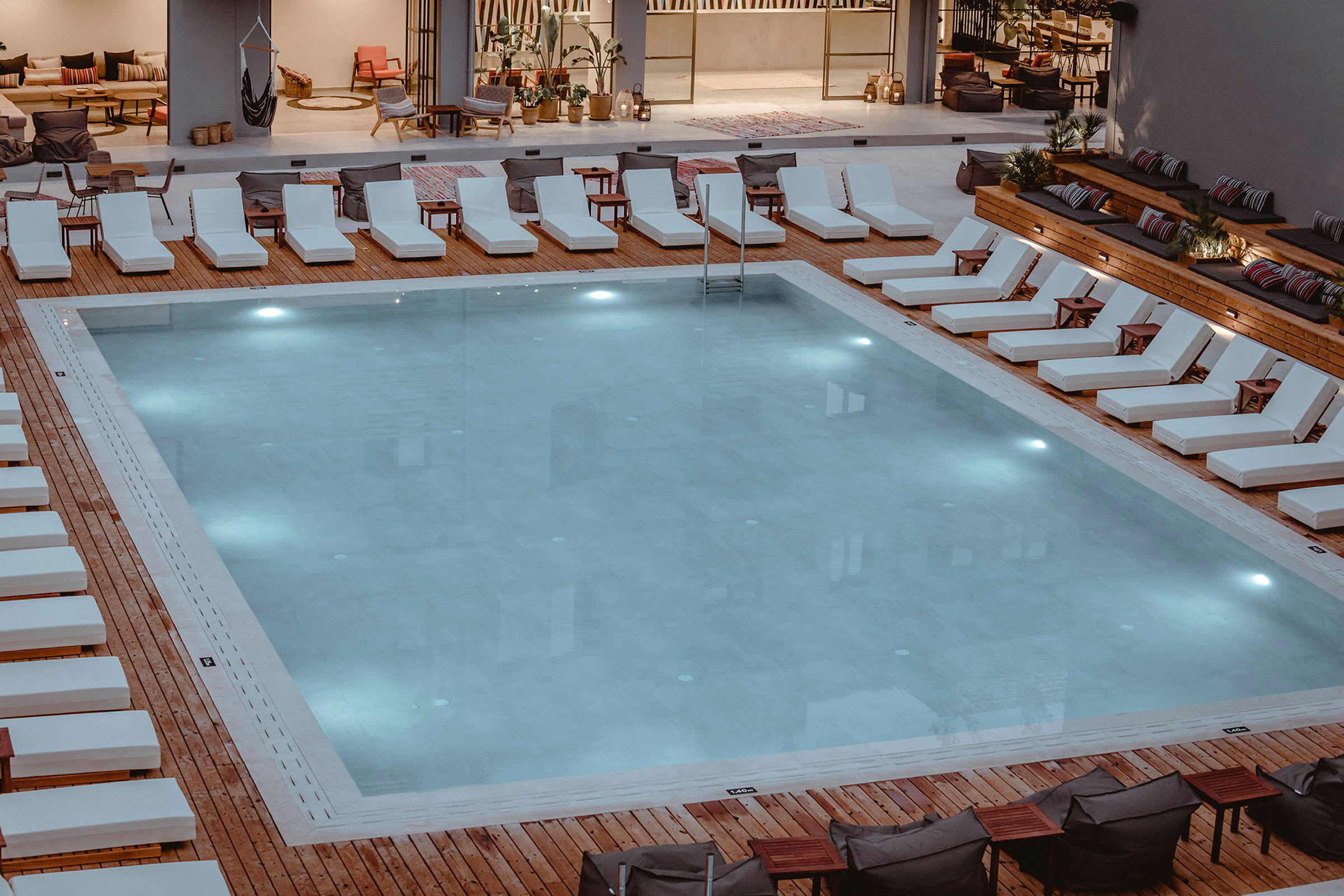 En pool omgiven av solstolar och sittplatser. (AI-genererad text)