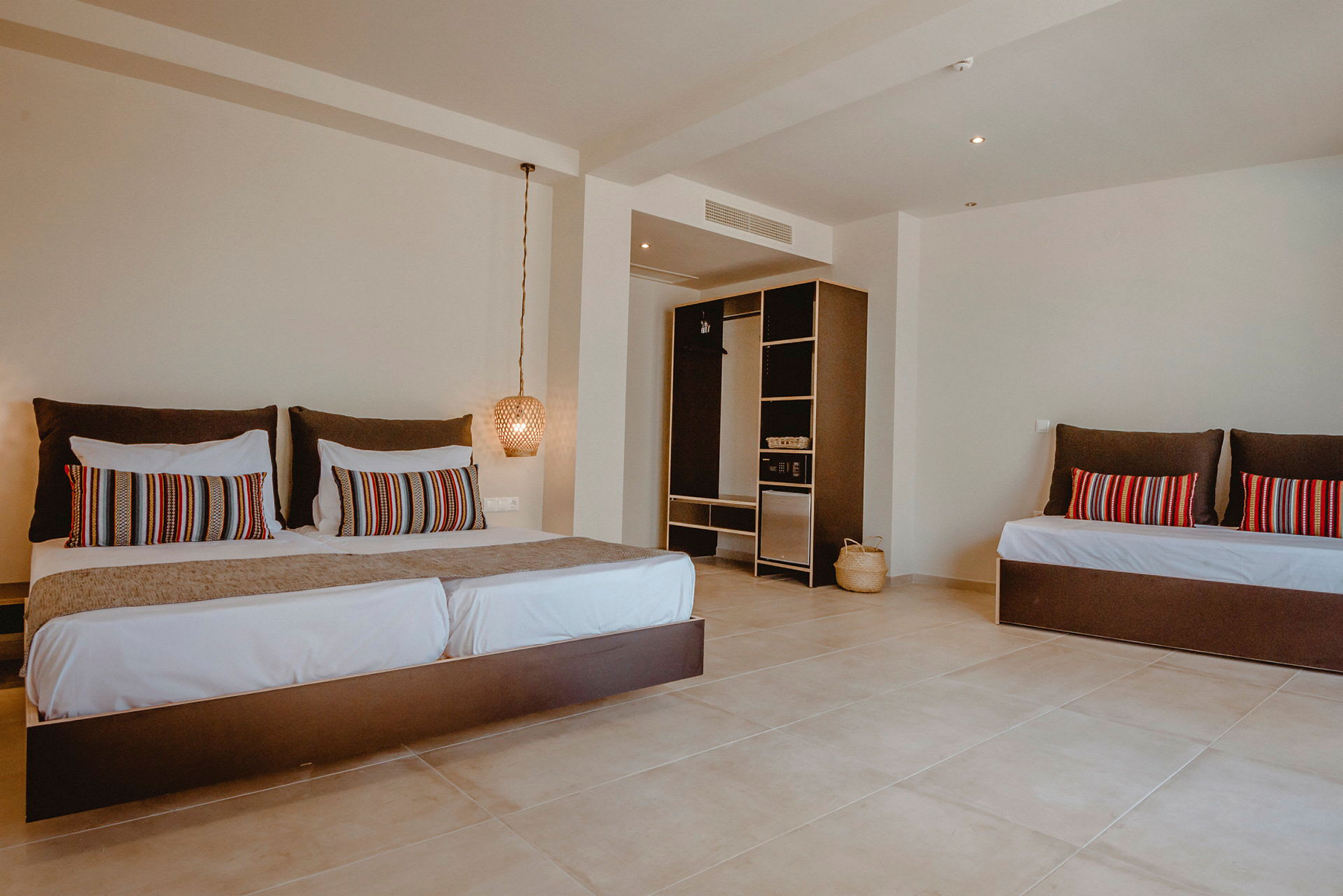 Ett hotellrum med en stor säng, dekorativa kuddar och en öppen garderob. (AI-genererad text)