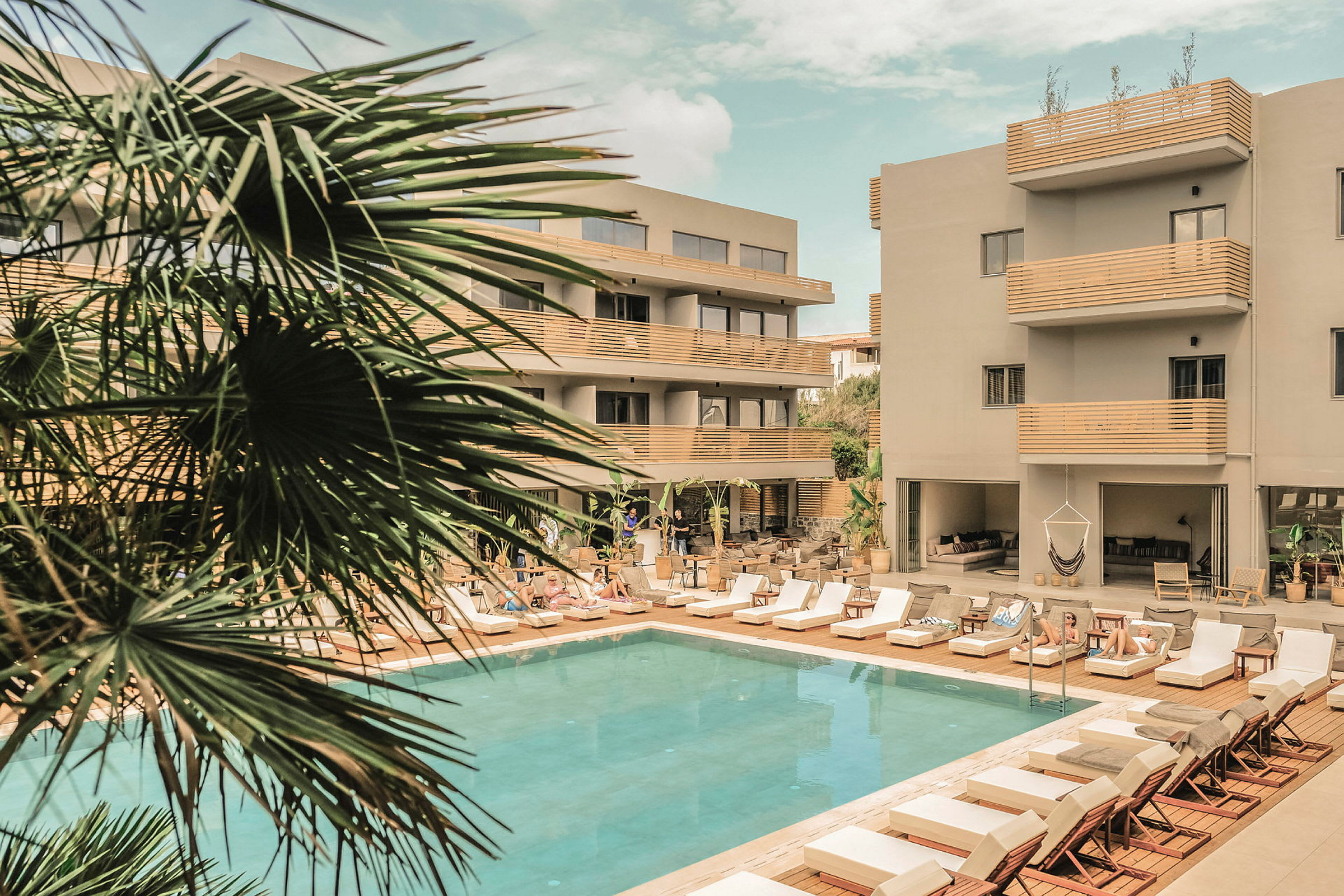 Hotell med pool och solstolar omgivna av palmer. (AI-genererad text)