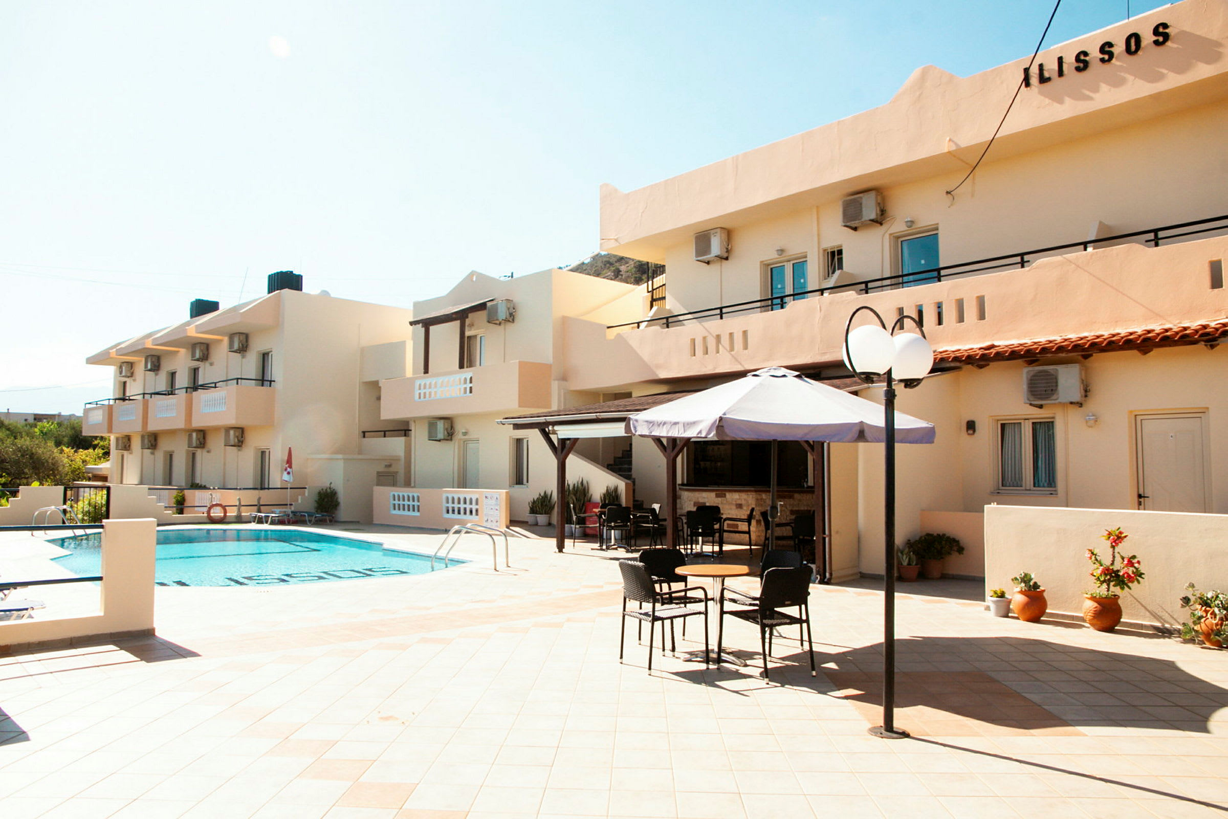 Utomhusområde vid hotell med en pool, parasoll och sittmöbler. (AI-genererad text)
