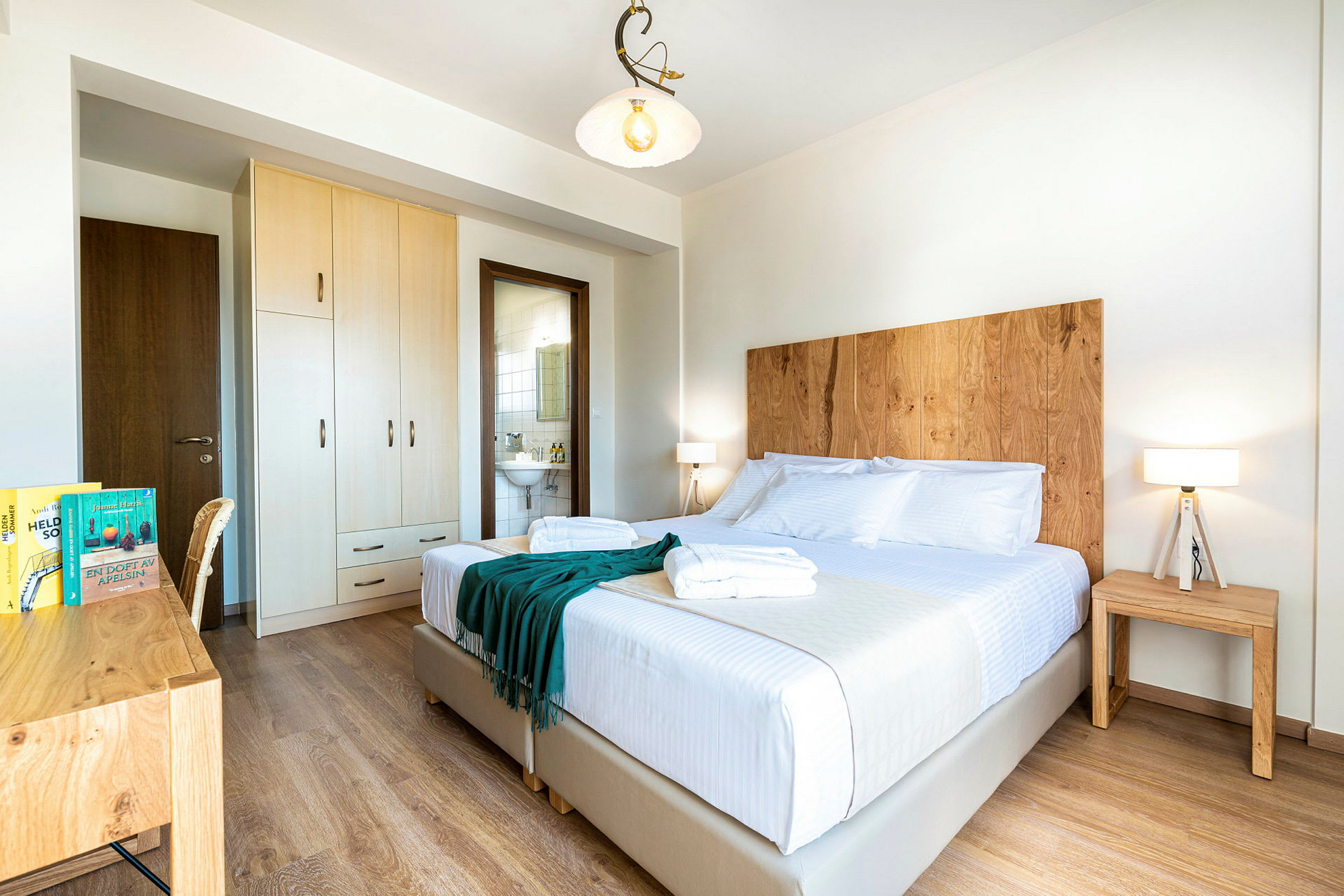 Ett ljust hotellrum med dubbelsäng, trädetaljer och är välstädat. (AI-genererad text)