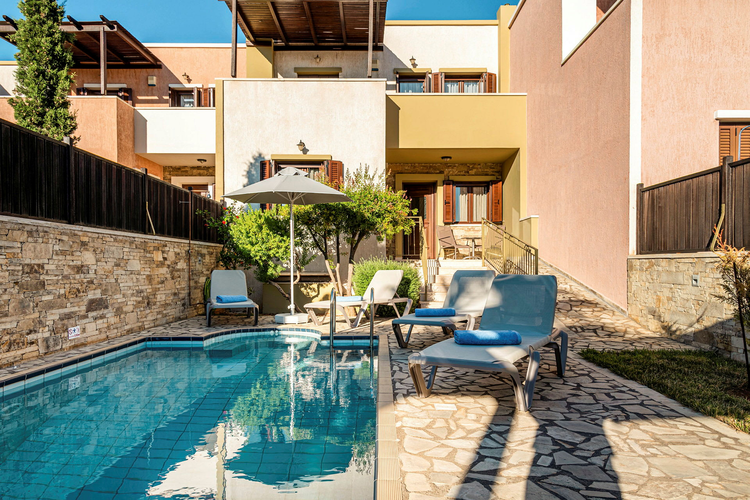 En trädgård med pool, solsängar och ett hus i bakgrunden. (AI-genererad text)
