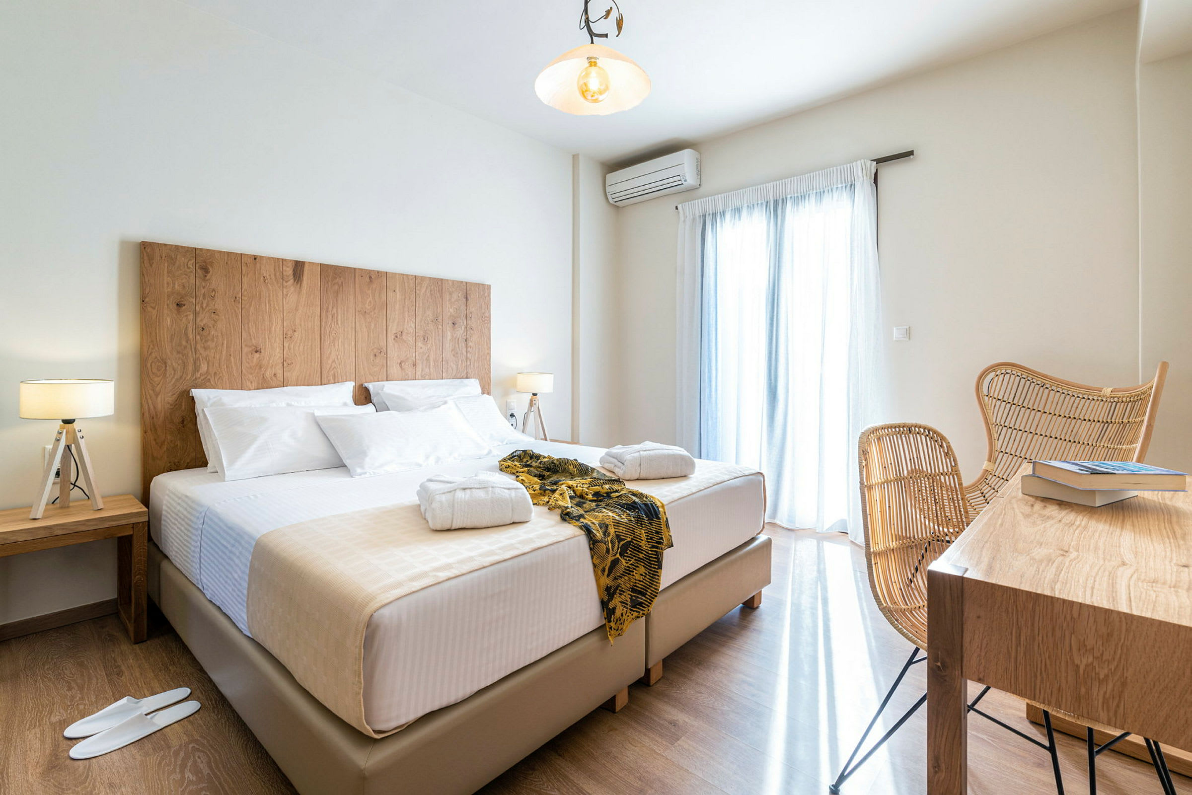 Hotellrum med en stor säng, sängbord med lampor samt en sittgrupp och bort med böcker. (AI-genererad text)