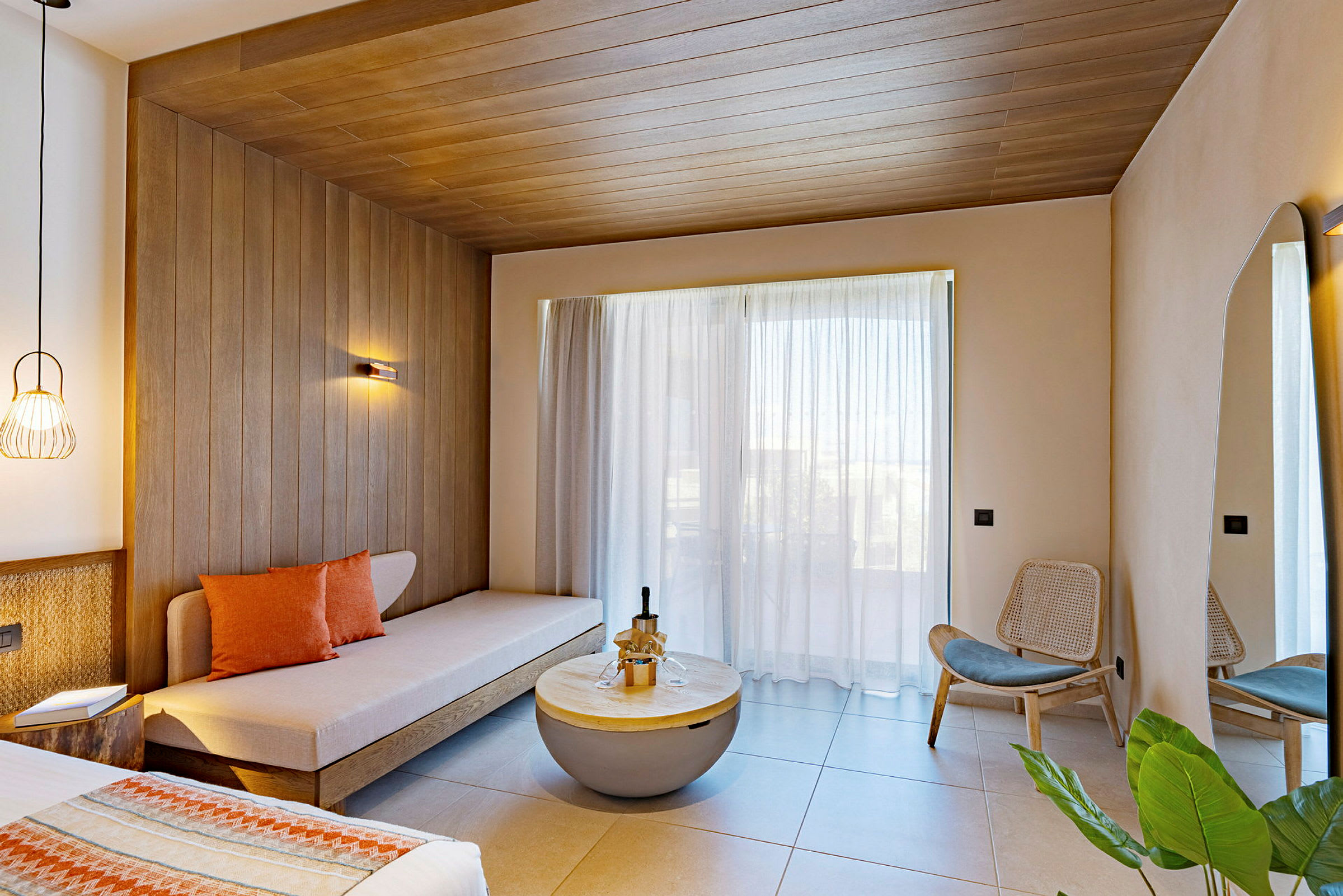 Ett modernt hotellrum med soffa, träpaneler, stora glasfönster och stilfull inredning. (AI-genererad text)