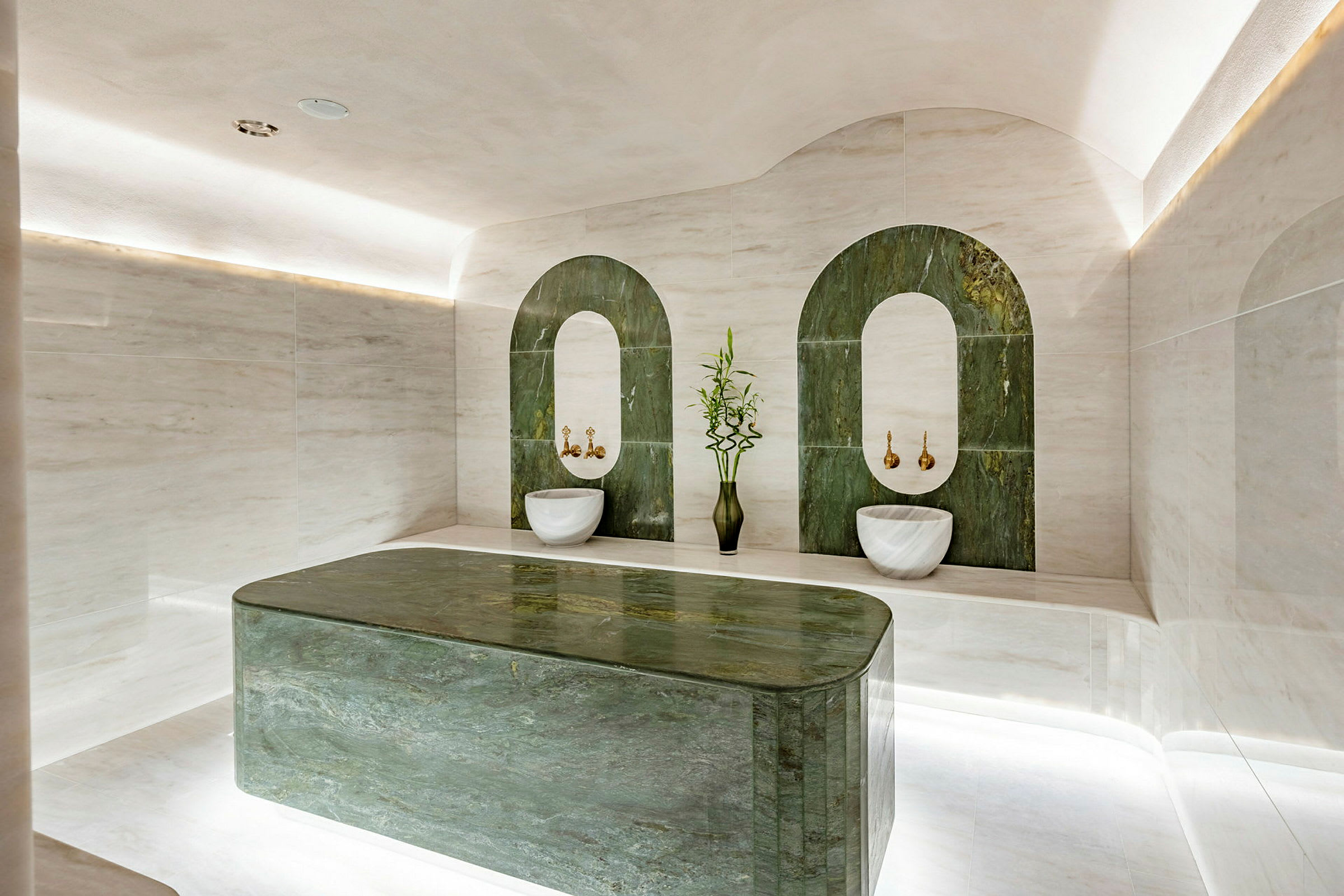 Bild av ett elegant hamam med gröna marmordekorationer och vita stenmaterial. (AI-genererad text)