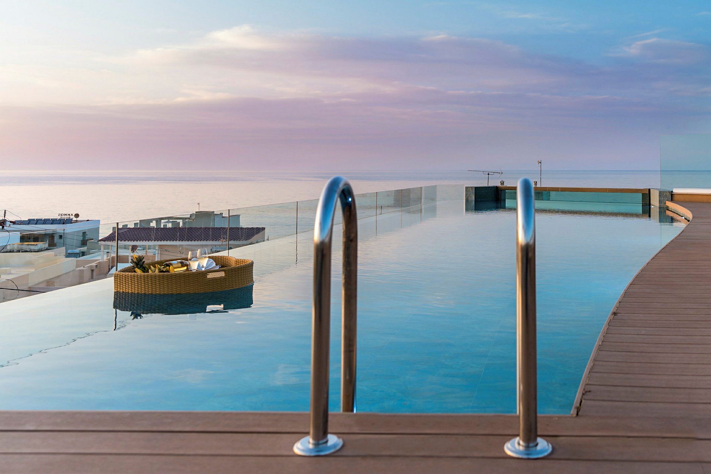 En pool med utsikt över havet och himmeln vid solnedgång. (AI-genererad text)