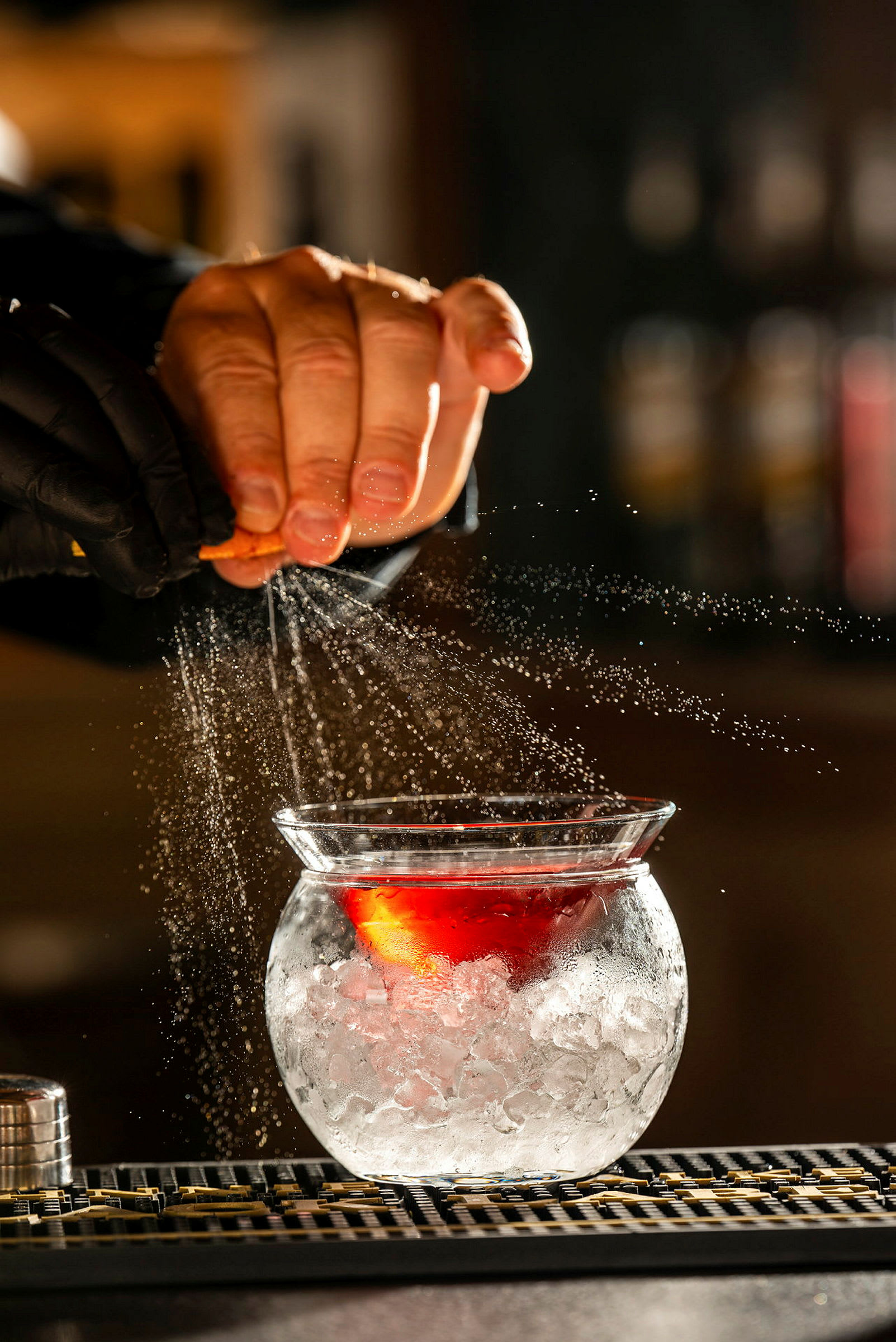 En hand som pressar citrus över ett glas med is och en mörkröd vätska. (AI-genererad text)