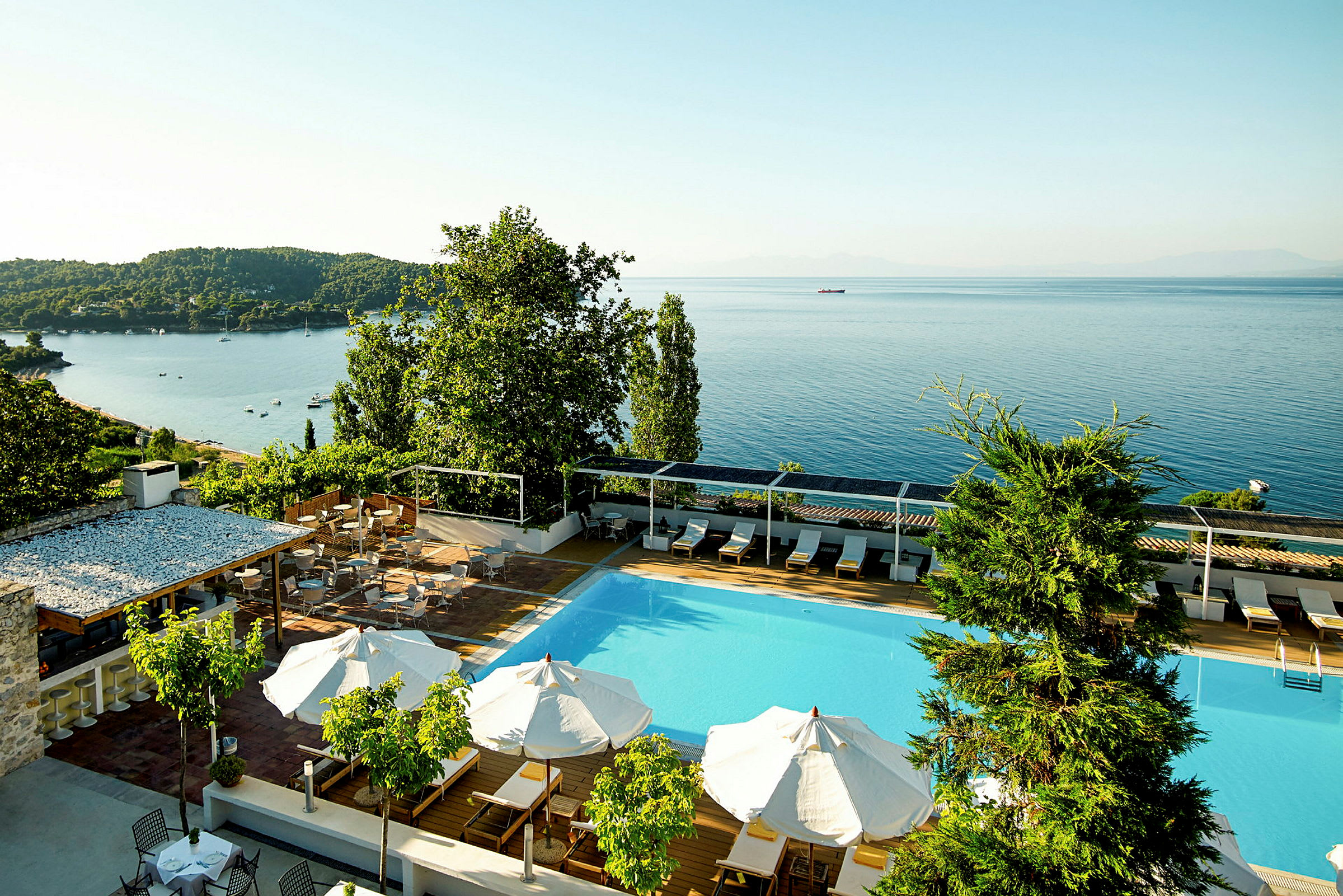 Hotellpool med utsikt över havet och grönskande omgivningar. (AI-genererad text)
