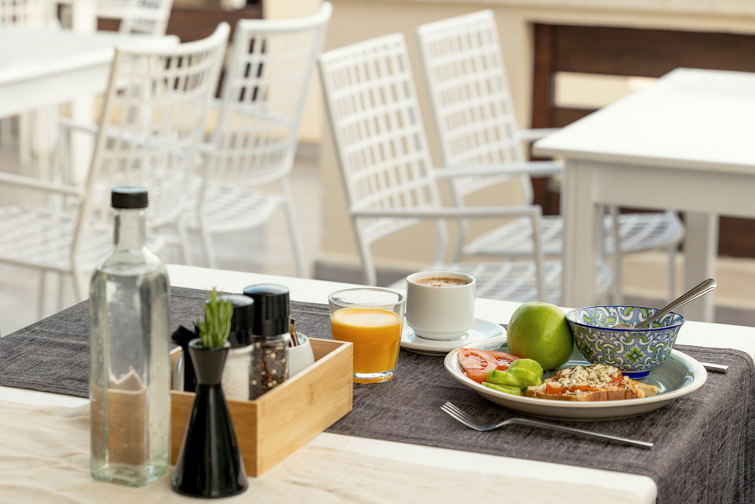 Ett dukat bord med frukost: kaffe, juice, frukt och bröd. (AI-genererad text)