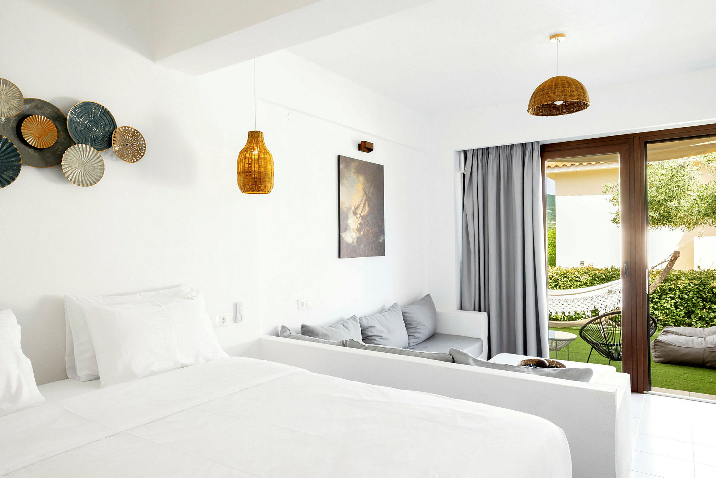 Ett hotellrum med ljus inredning och öppning mot en terrass med grönska. (AI-genererad text)