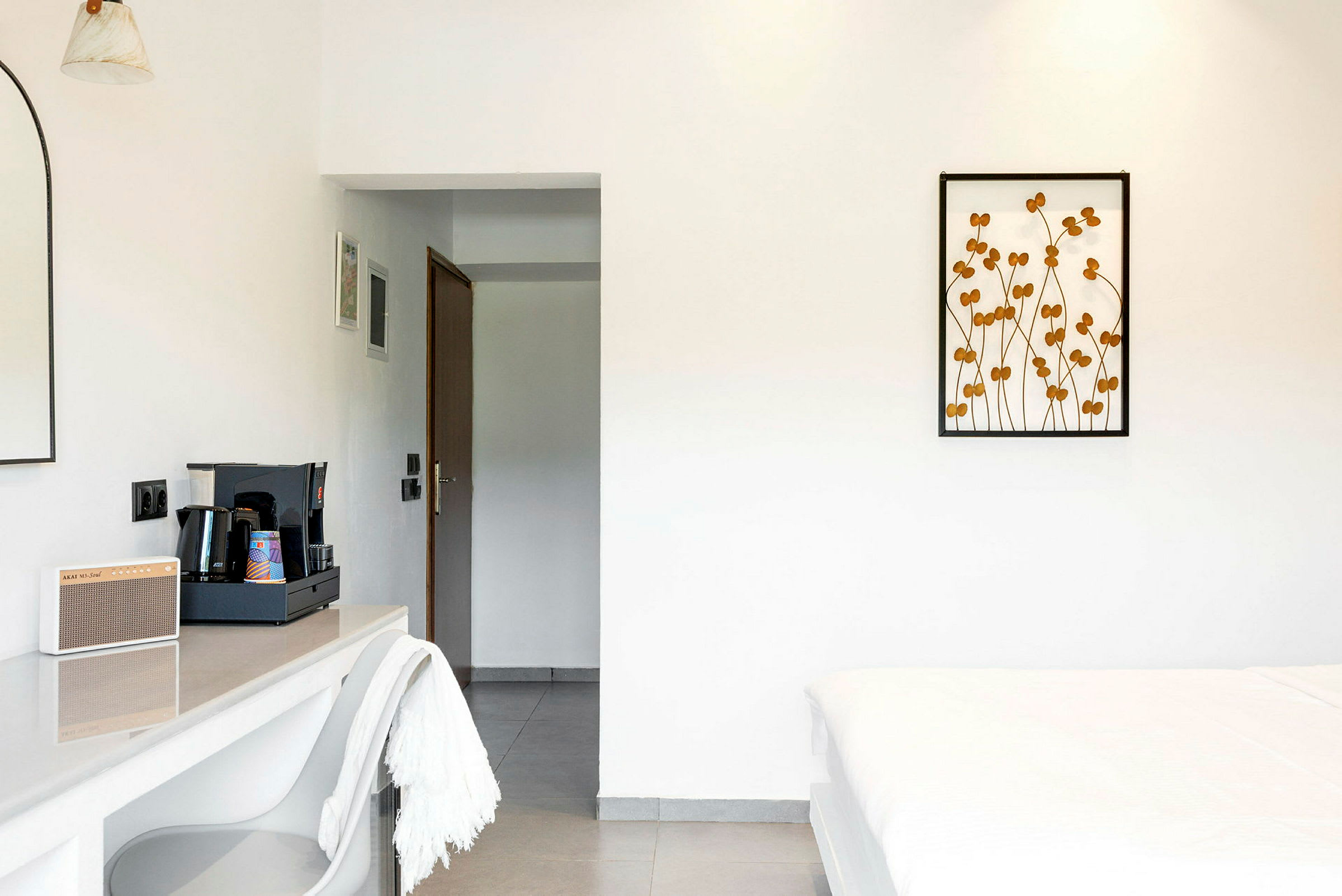 Ett hotellrum med minimalistisk inredning, inklusive en kaffestation och en säng. (AI-genererad text)