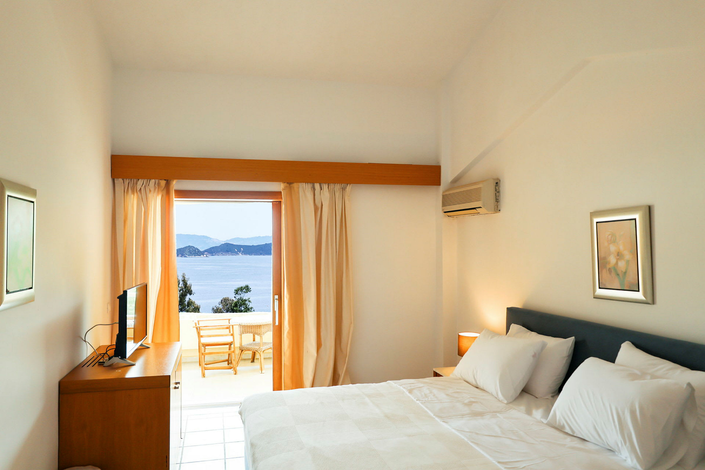 Hotellrum med en dubbelsäng och utsikt över havet från en balkong. (AI-genererad text)