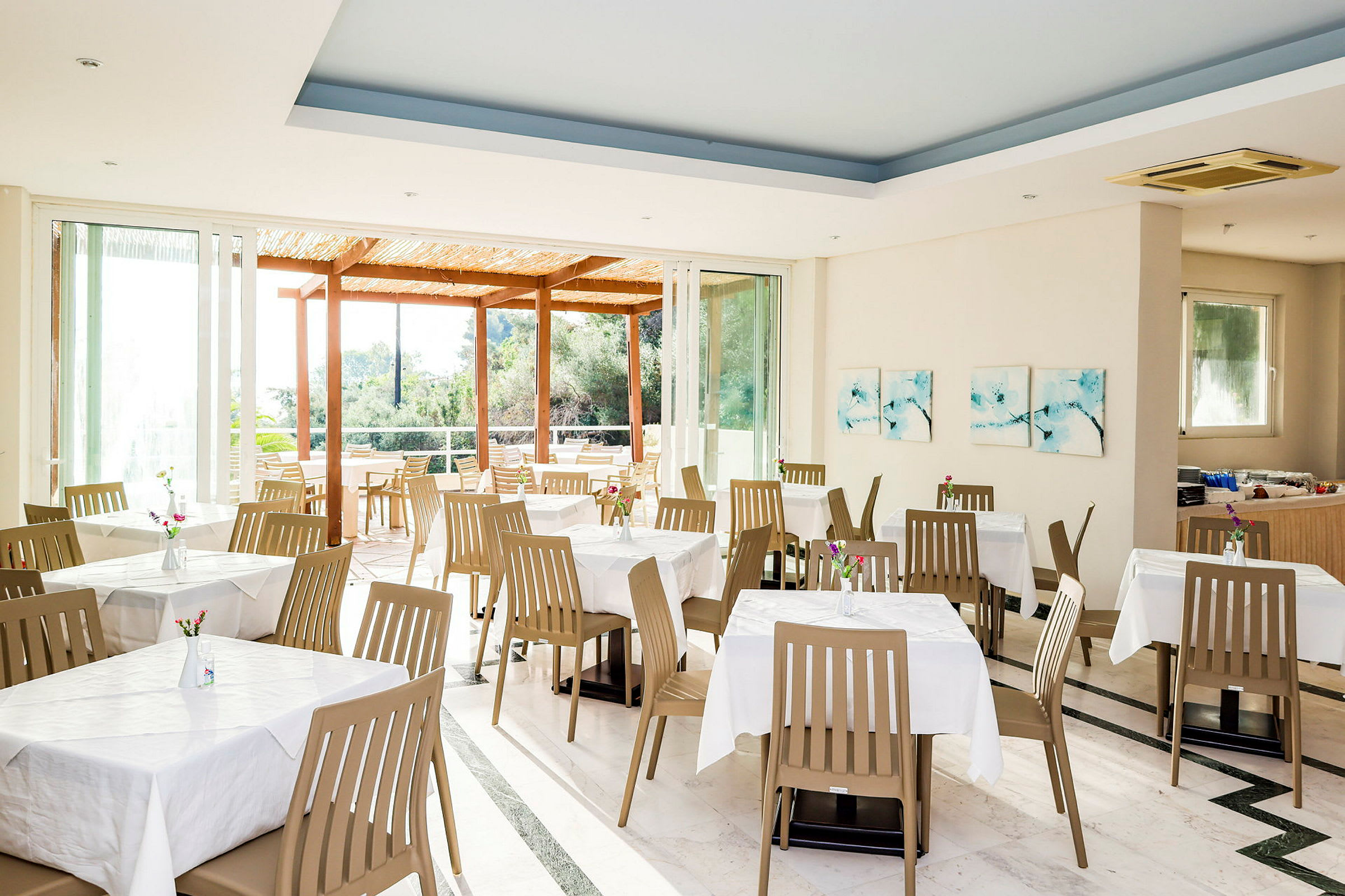 Restaurang med dukade bord och stolar, samt stora fönster med utsikt. (AI-genererad text)