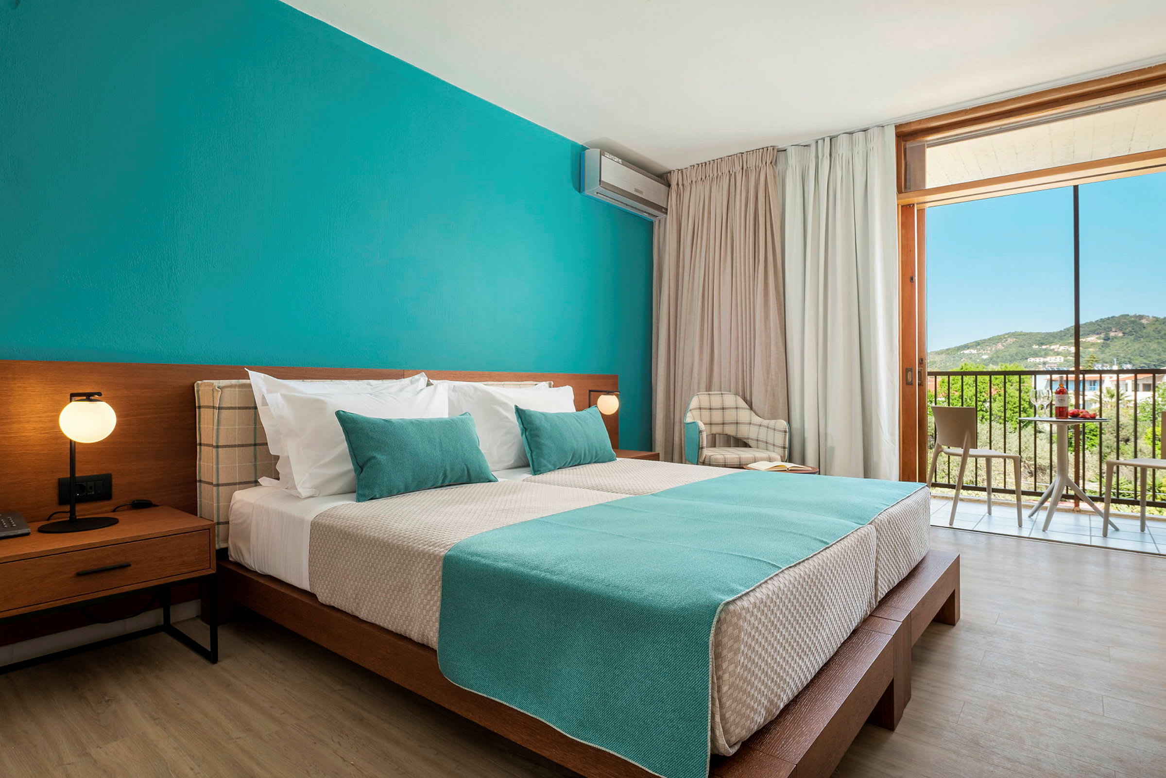 Ett hotellrum med en stor säng och blå väggar samt utsikt genom en balkong. (AI-genererad text)