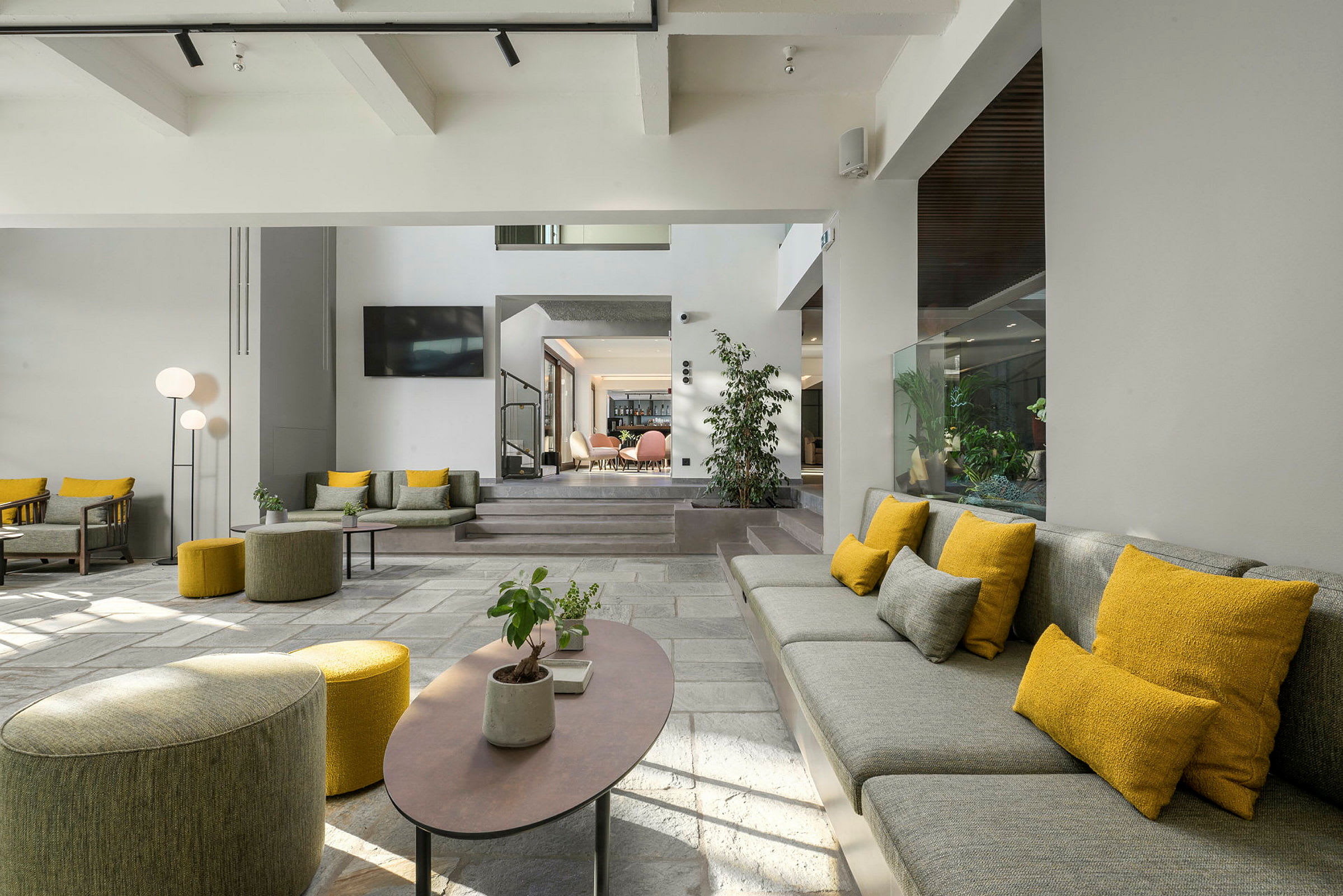 En modern hotellobby med sittmöbler i grått och gult. (AI-genererad text)