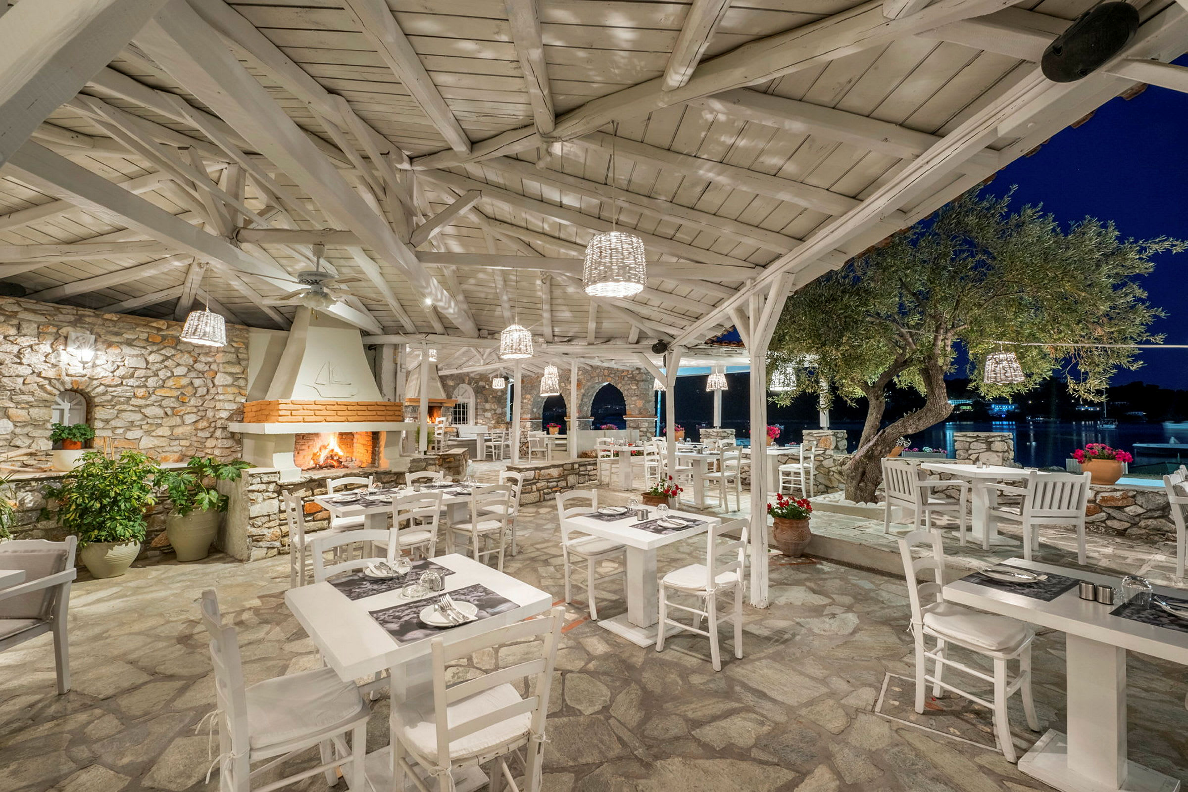 Utomhus restaurang med vita möbler och stenbeklädd inredning. (AI-genererad text)
