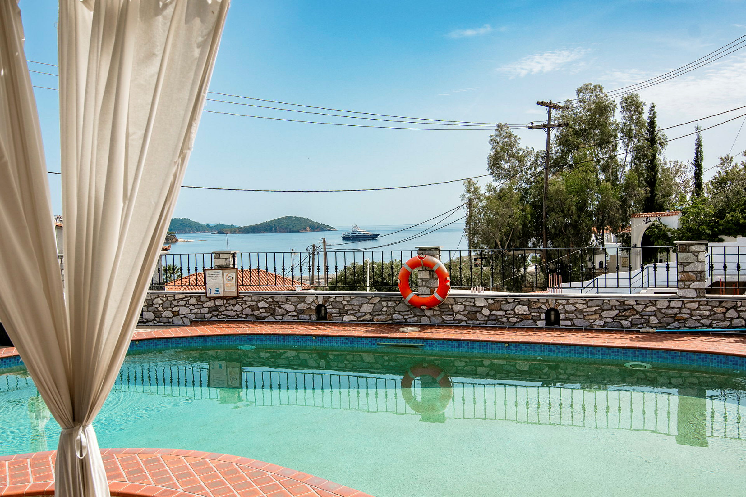 Utsikt över en pool med havet och en yacht i bakgrunden. (AI-genererad text)