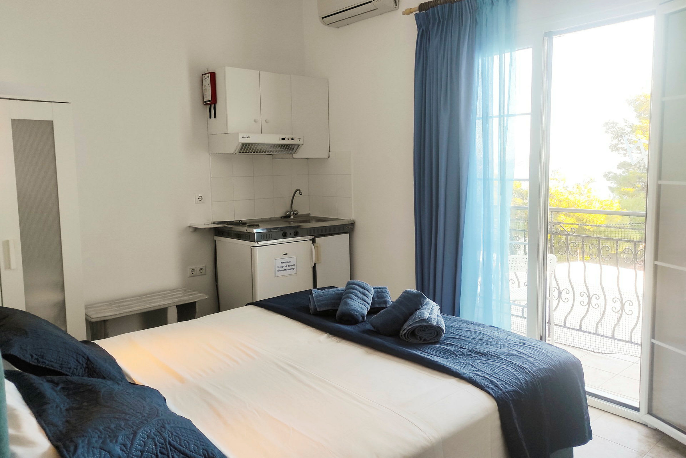 Hotellrum med säng, köksdel och balkong med utsikt. (AI-genererad text)