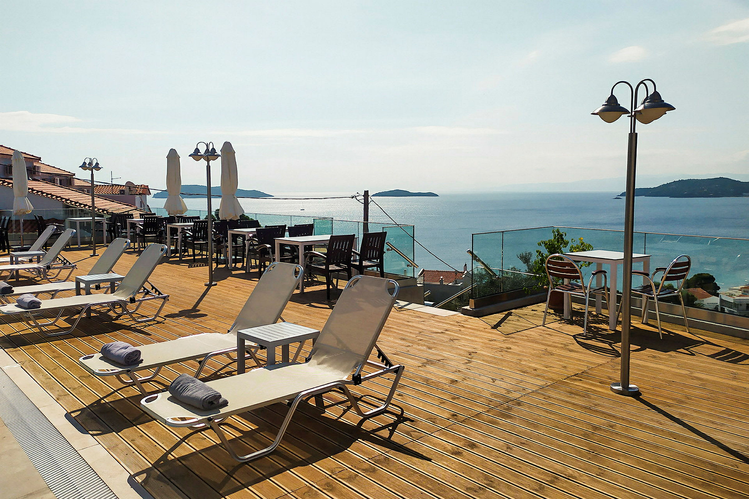 En terrass med solstolar, bord och stolar samt utsikt över havet. (AI-genererad text)