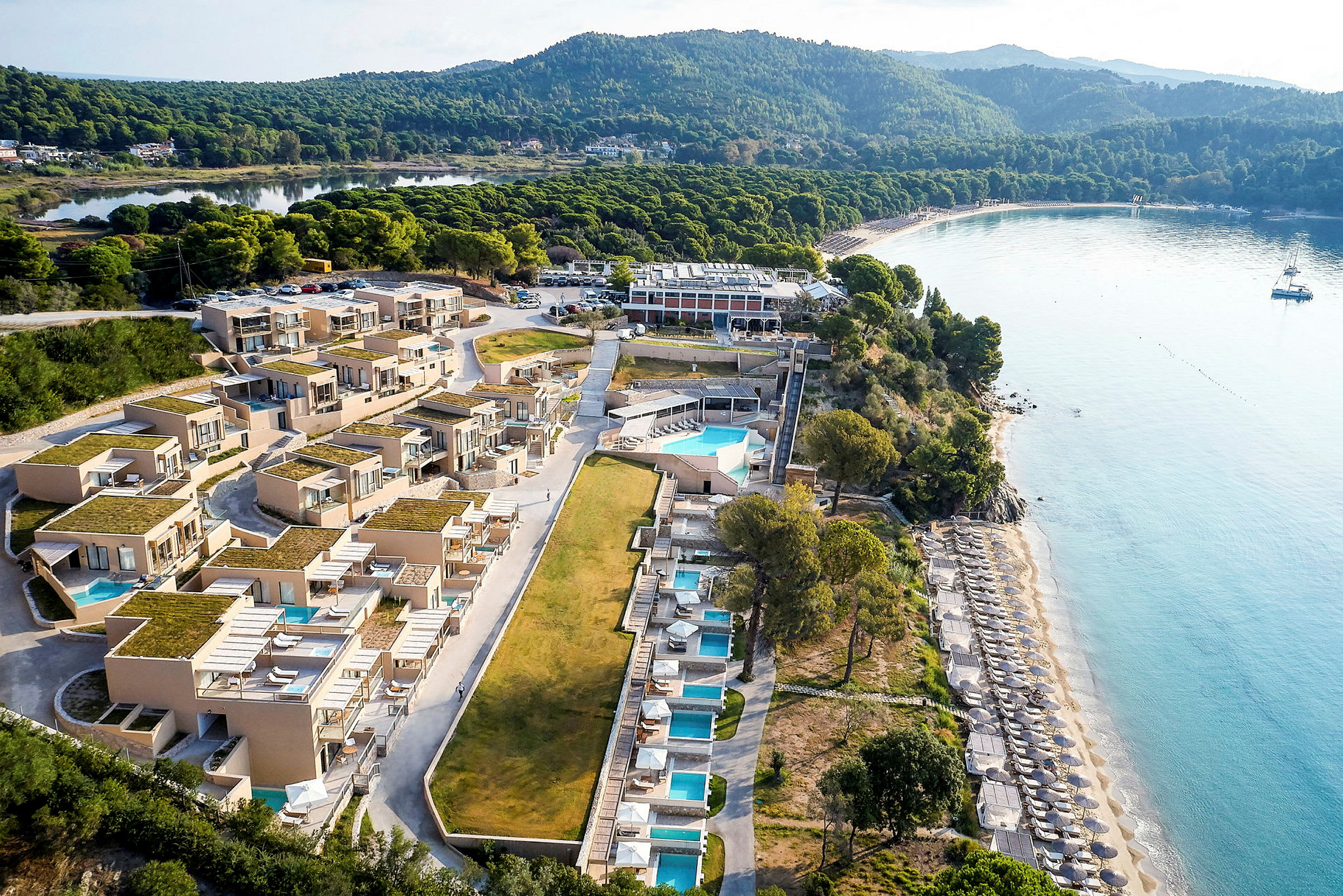 Flygfoto av ett strandnära hotell med pooler och solbäddar. (AI-genererad text)